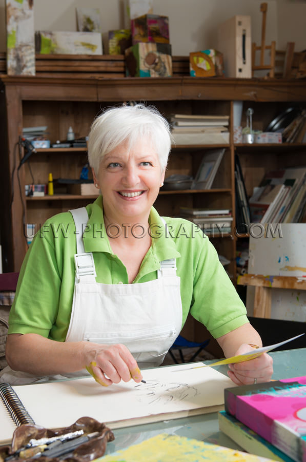 Ältere Frau Lächeln Und Zeichnen In Atelier Stock Foto