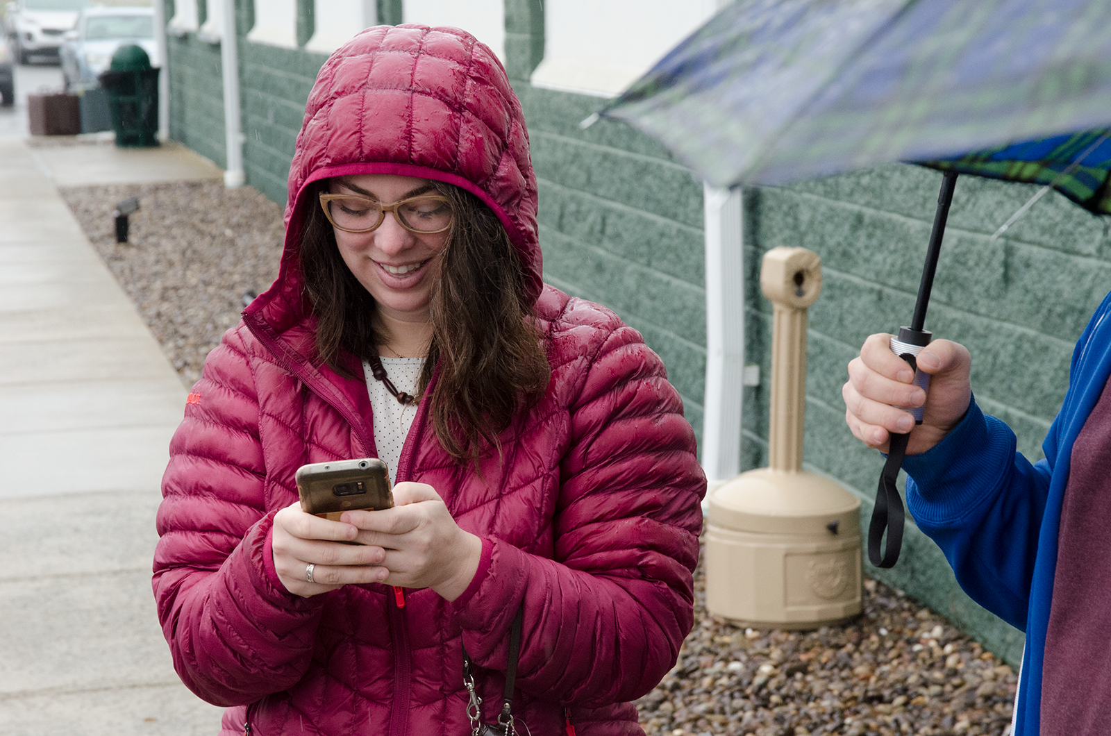 Jenna waits for Morgantown Social Club members in the rain outside Empty Bowls, communicating with people who are on the way.