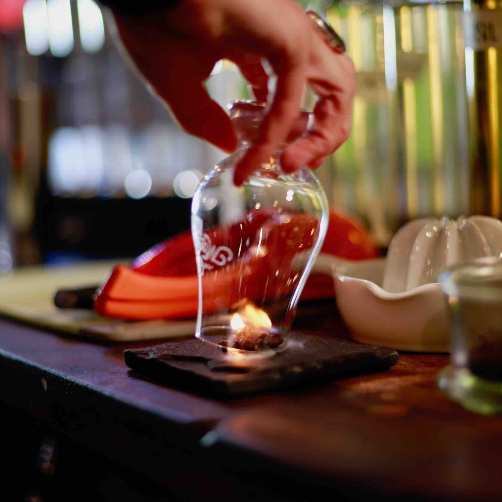 Montanya bartender places a glass over burning cloves to make the Smokeshow cocktail.