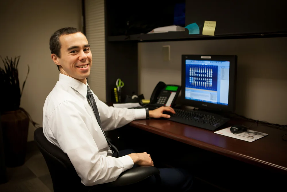 Dr. Kevin Suzuki sitting at his desk reviewing a patient file.