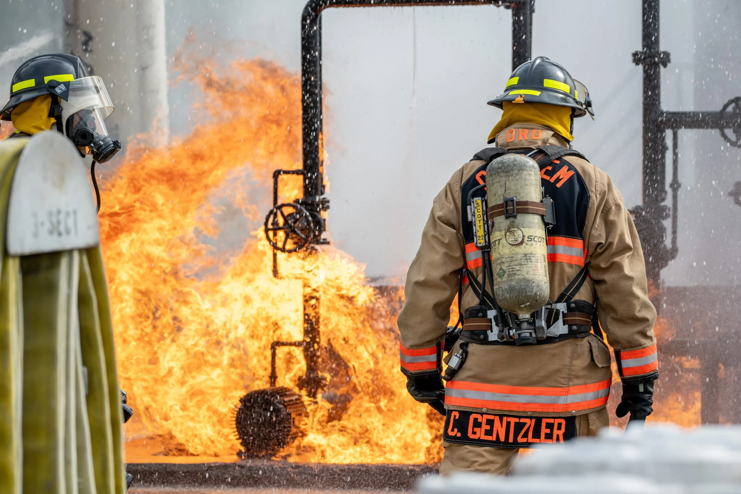 Firefighters battling a large blaze with flames and thick smoke.