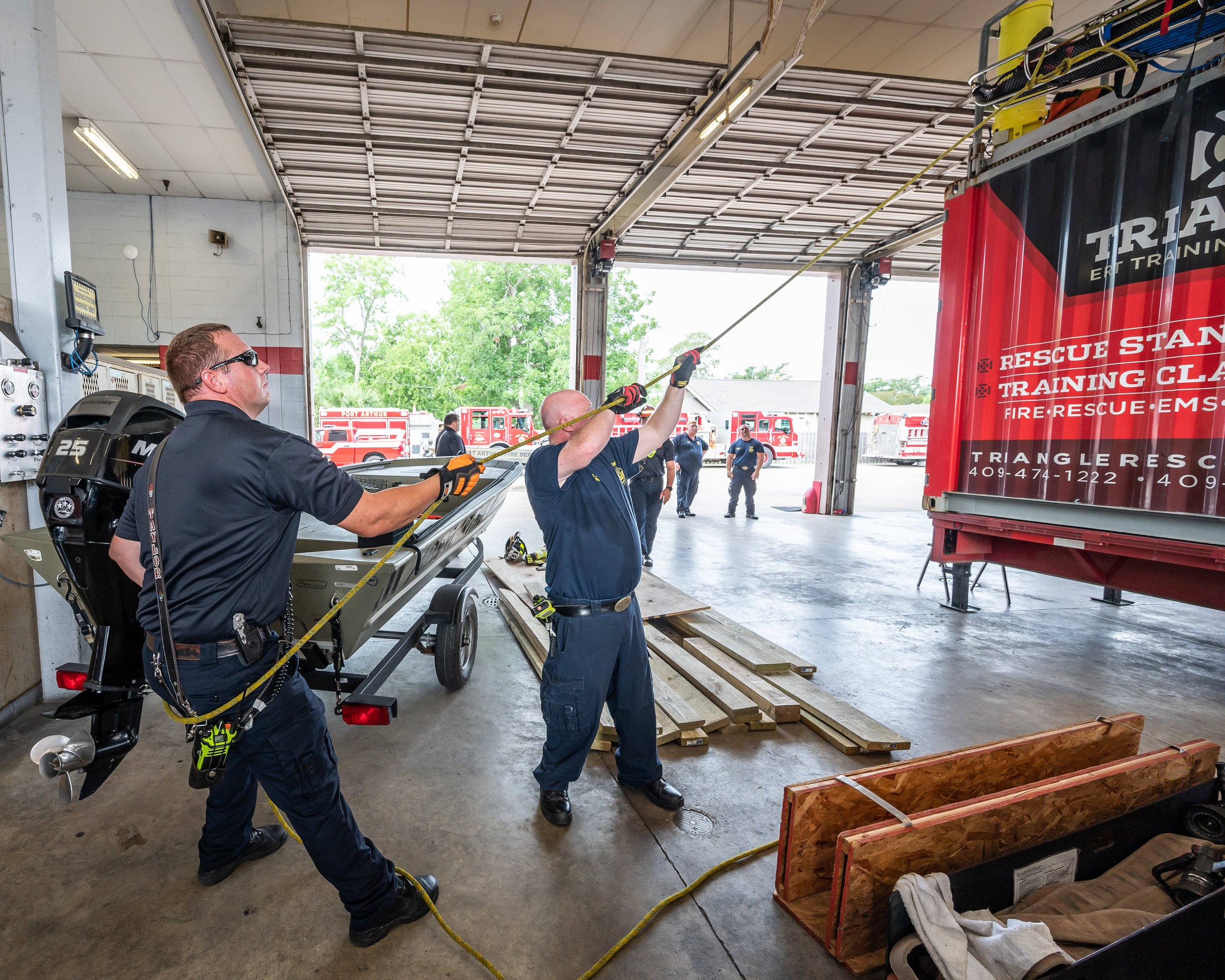 Firefighters practicing rope rescue techniques inside a fire station.