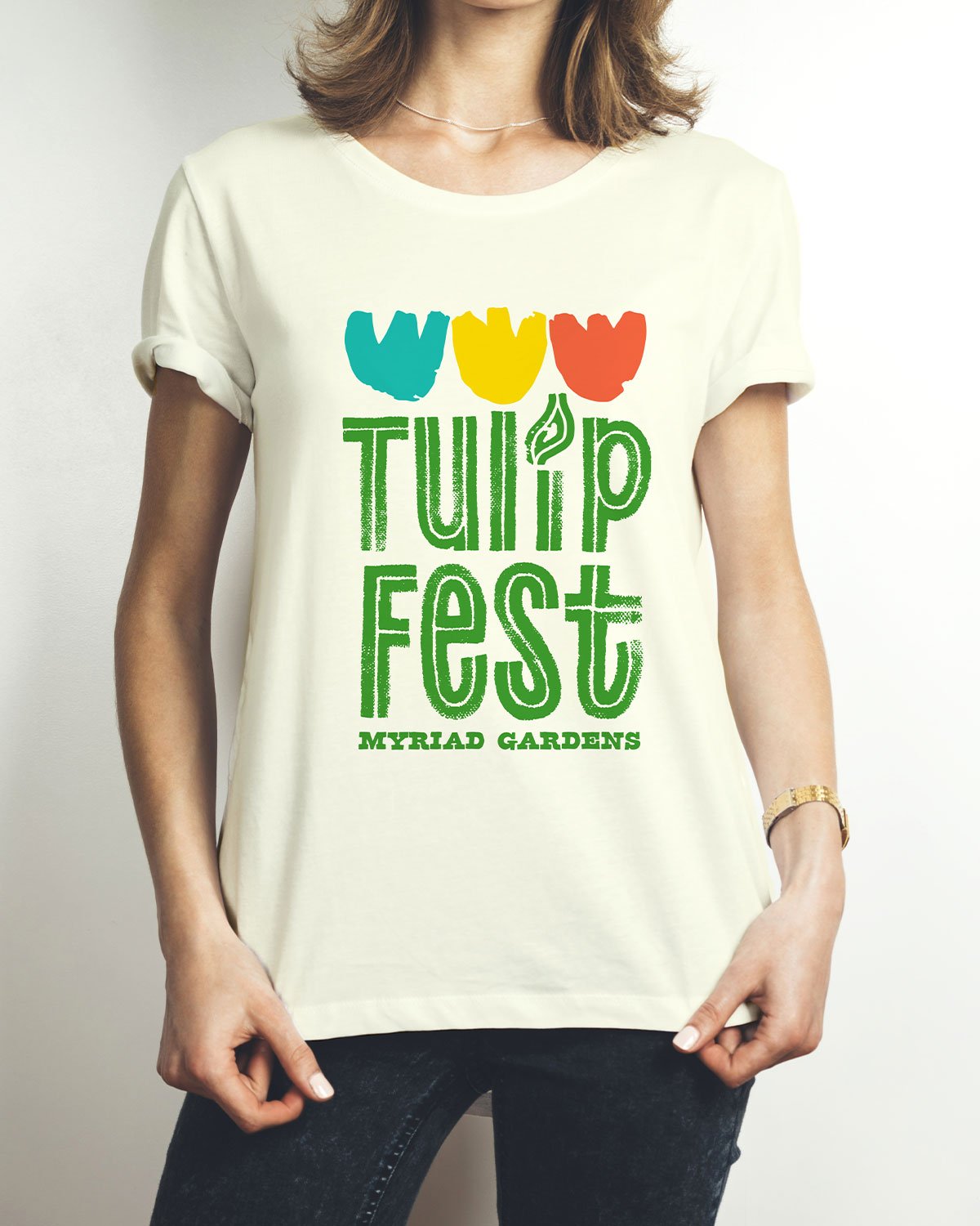 A woman wearing a T-shirt with colorful tulip graphics and green text that reads "Tulip Fest" and "Myriad Gardens."