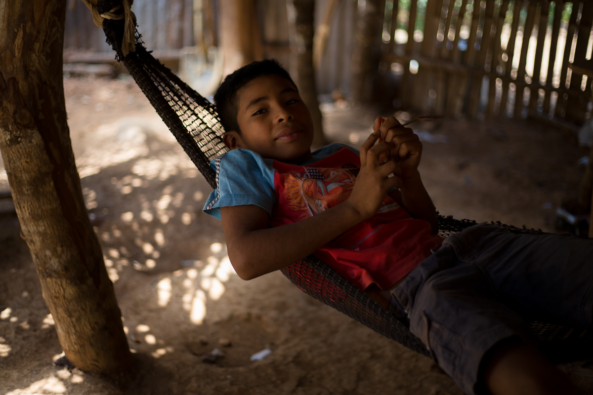 2019. Junior relaxes in his home. Even with the subsidies, not all families can afford the conversion to cement just yet.