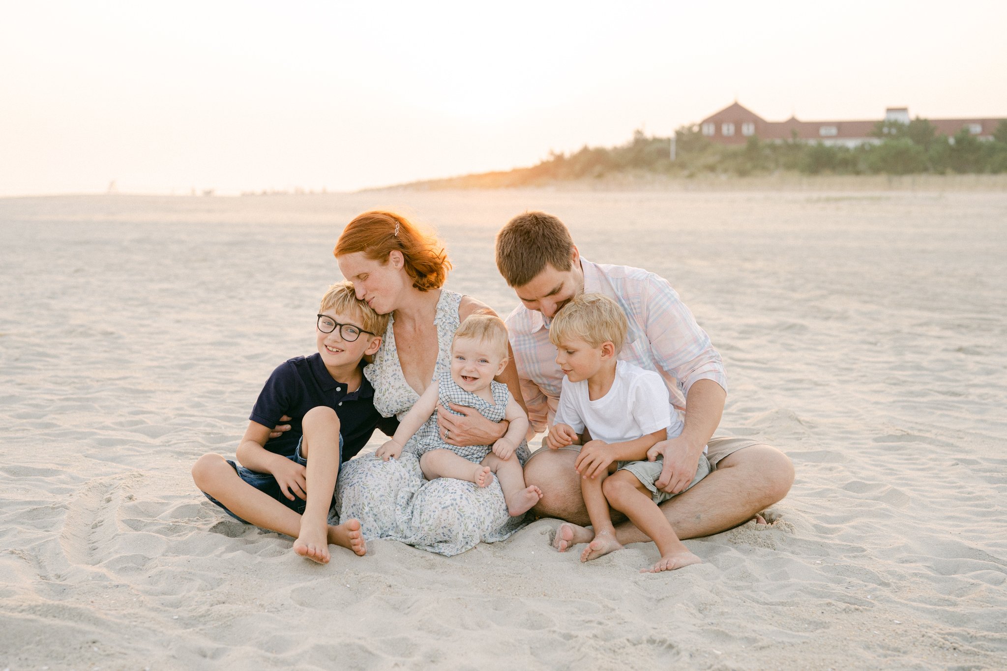 family sits on the beach at sunset in Cape May NJ