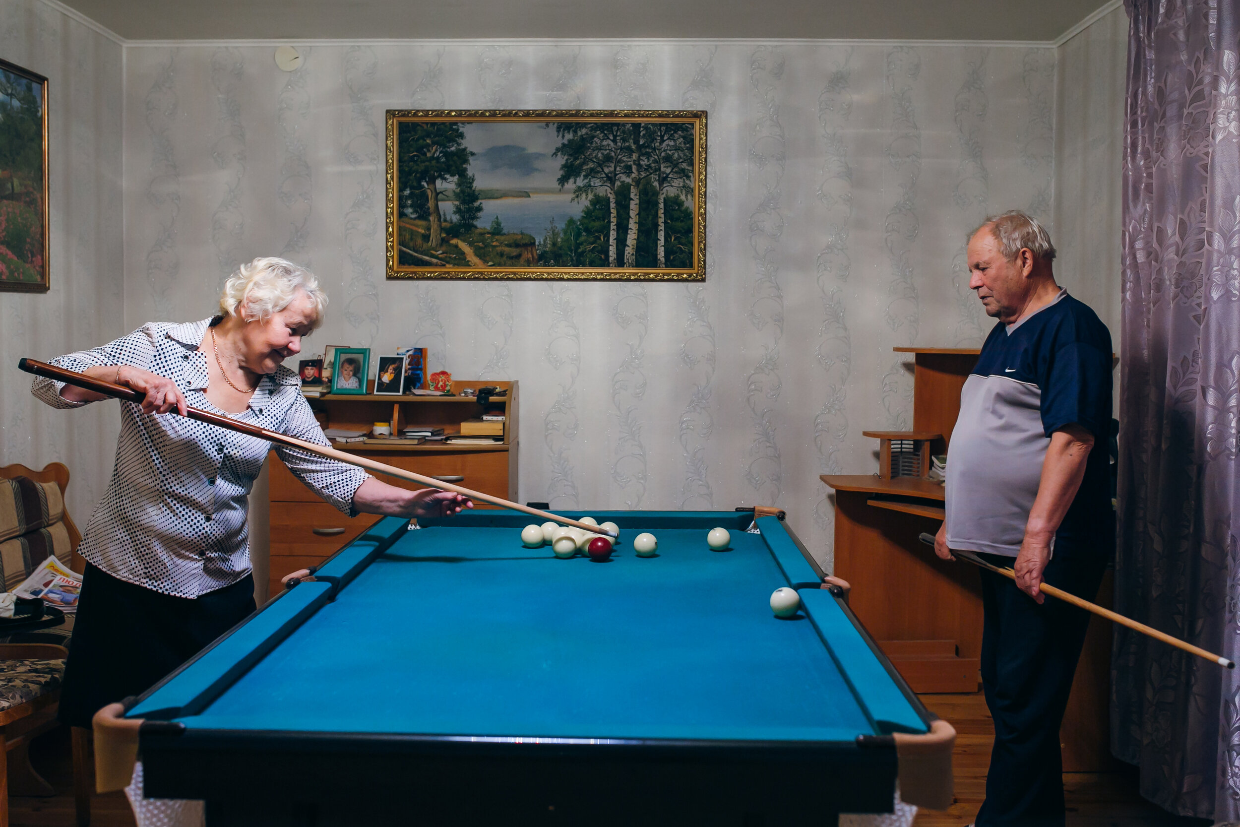  Antonina and Nikolay are playing pool at Nikolay’s home. He teaches Antonina the way to hold the cue.     