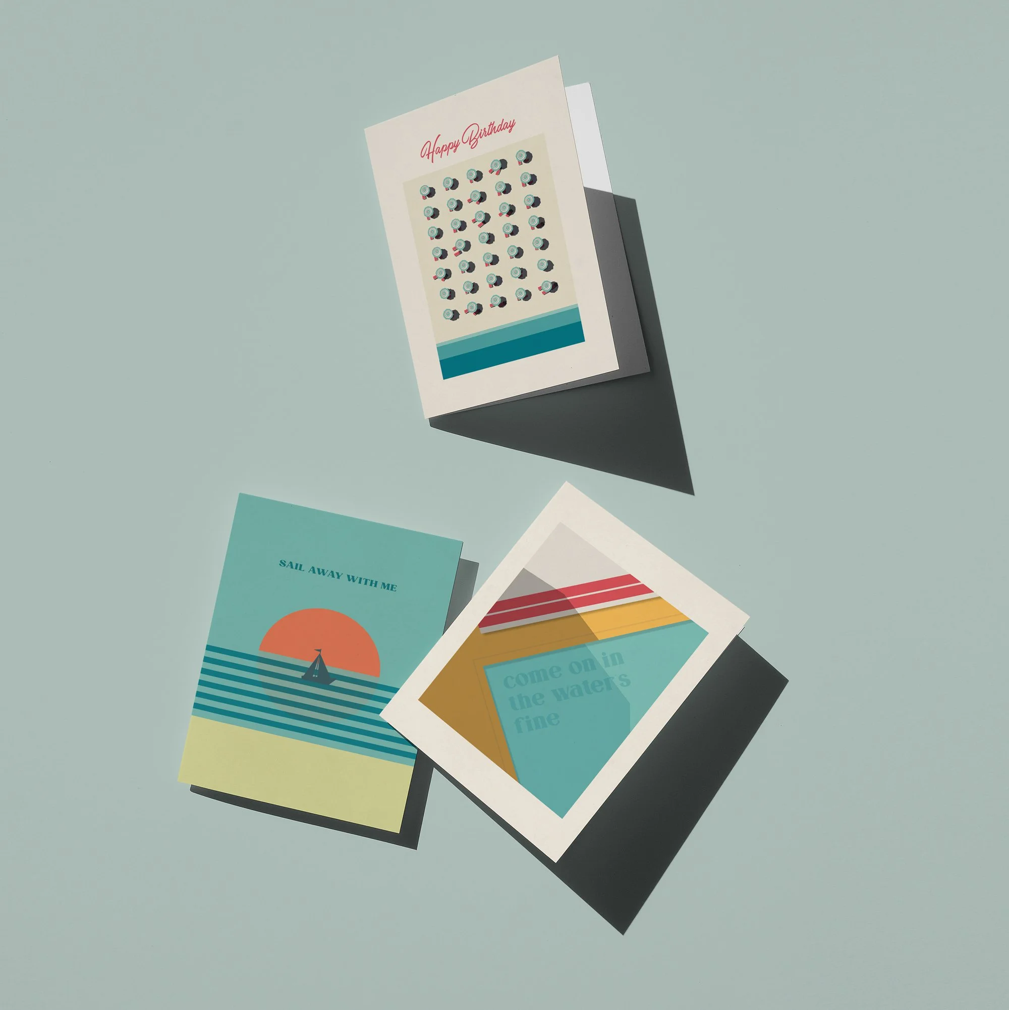 Three greeting cards with different designs and messages, arranged on a light-colored surface.