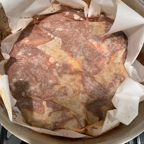 Press parchment directly on the meat and sauce to keep the meat from drying out.