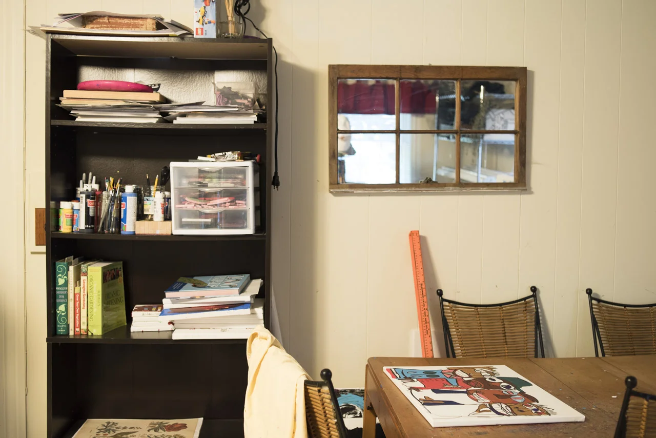 The workspace table & art supply shelves.