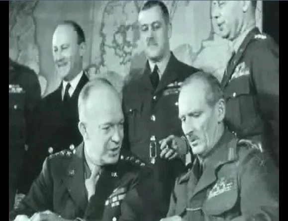 Captain James Martin Stagg (front right) in discussions with General Dwight “Ike” Eisenhower (front left)