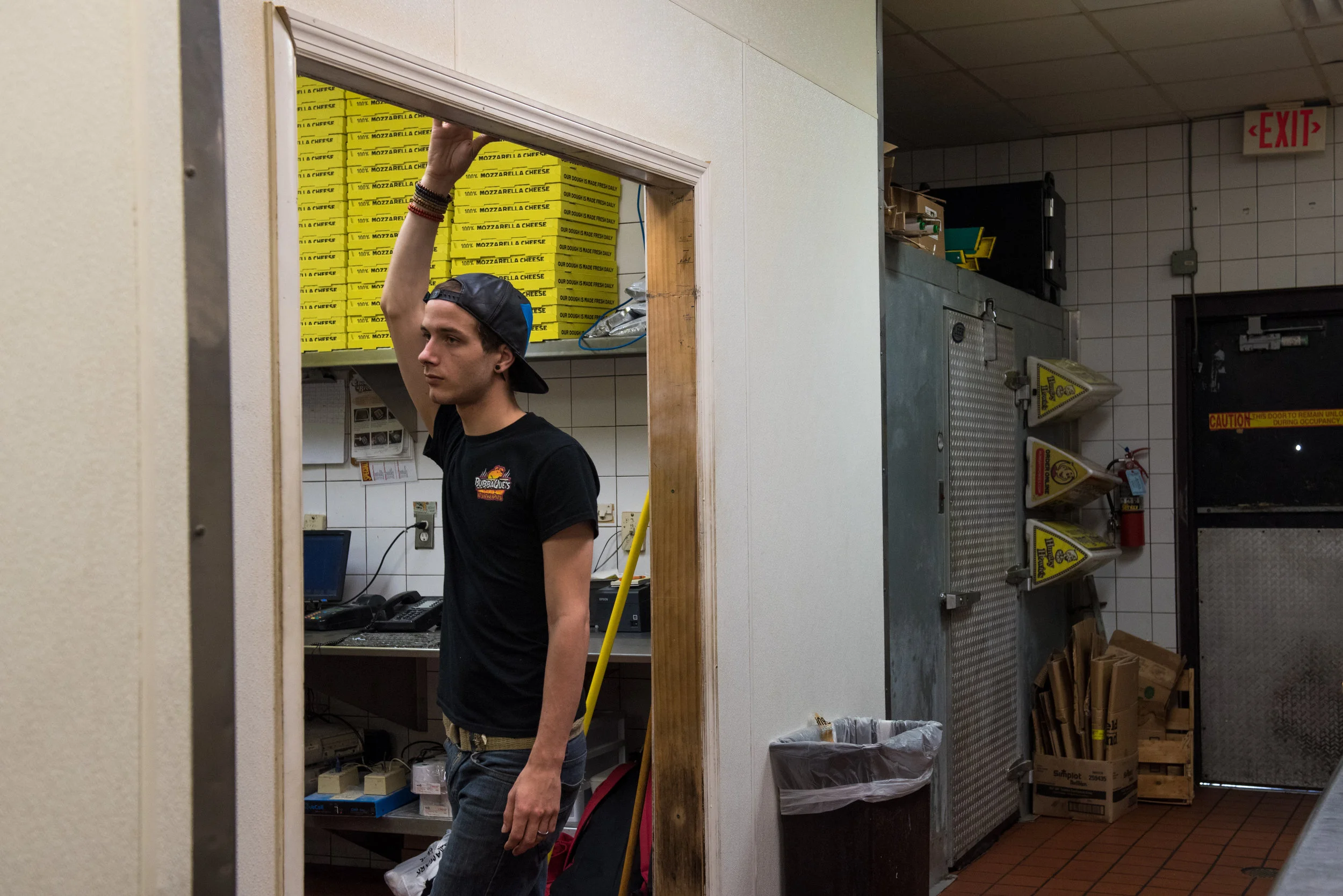 Koedam rests at the doorway between Hungry Howie’s Pizza and BubbaQue’s, the barbecue restaurant where he works almost every week day. Koedam supports his drag career with the money he makes waiting tables, preparing orders and working the cash register.
