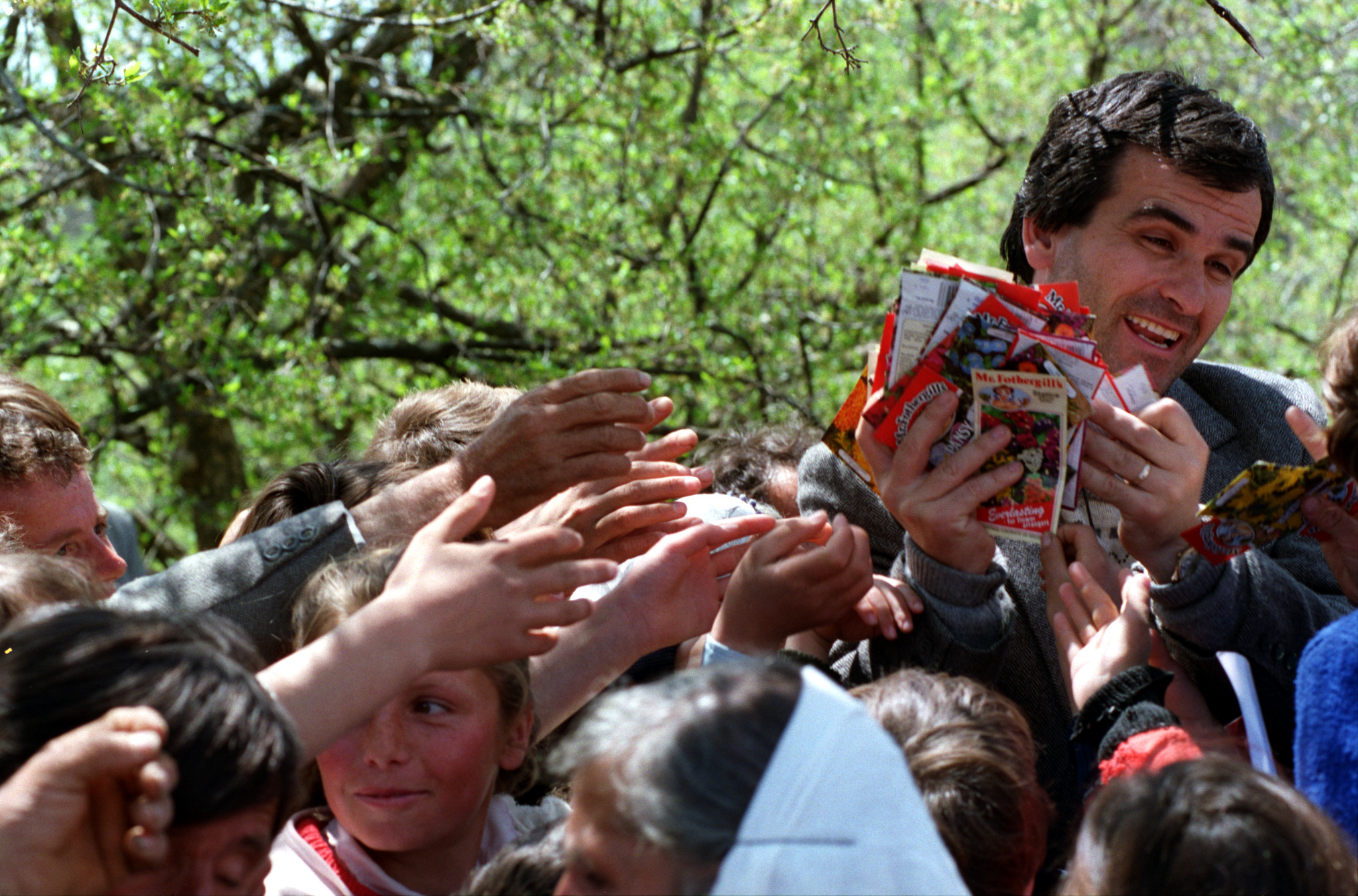  Artan Kosti, Father Martin Ritsi's assistant, hands out flower seed packets to enthusiastic villagers of Jeronisht. ©Gail Fisher Los Angeles Times 