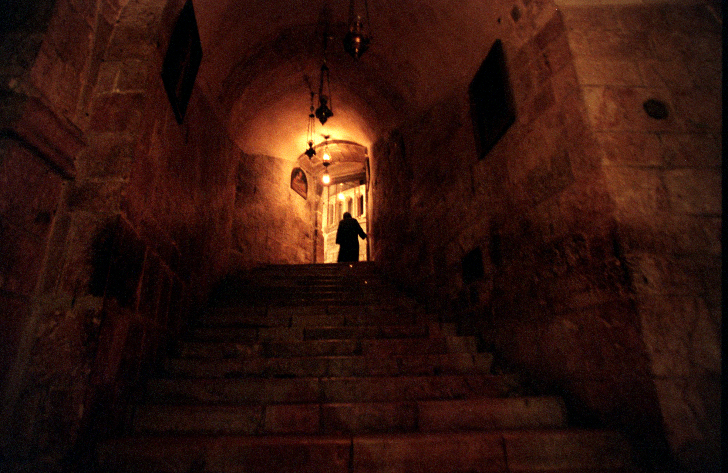 A Franciscan monk lights candles in the Church of the Holy Sepulcher, site of Christ's death, burial and resurrection located in the Old City of Jerusalem. ©Gail Fisher Los Angeles Times