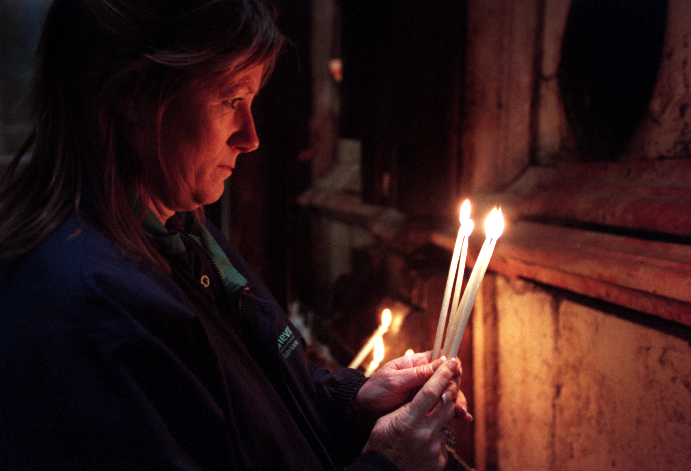  Interfaith member Melinda Griffith prays for sick family members and lights candles at Christ's tomb in the Church of the Holy Sepulcher, site of Christ's death, burial and resurrection, in the Old City of Jerusalem.&nbsp;©Gail Fisher Los Angeles Ti