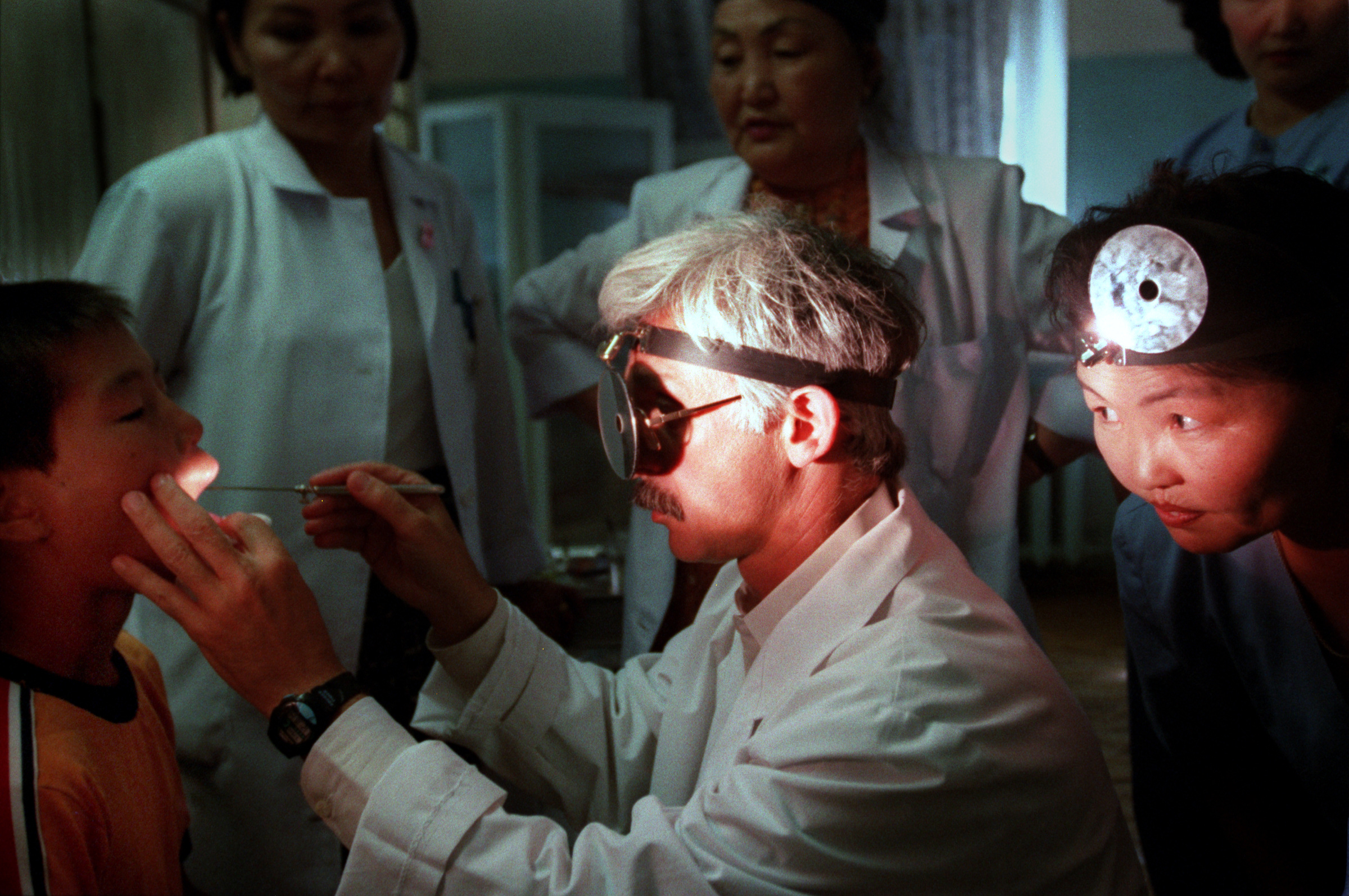Dr. Kenneth Geller, who runs the Division of Otolaryngology at Children's Hospital Los Angeles, examines Batbaatap, 10 years old, who suffered a crushed larynx when he was kicked by a horse at his family's home in the Mongolian countryside. Remoteness impedes delivery of health care, a problem exacerbated by rural stoicism that leads to delays in seeking medical help. When Batbaatap was injured nearly two months earlier, doctors could have helped restore his voice. Now it's too late. ©Gail Fisher Los Angeles Times
