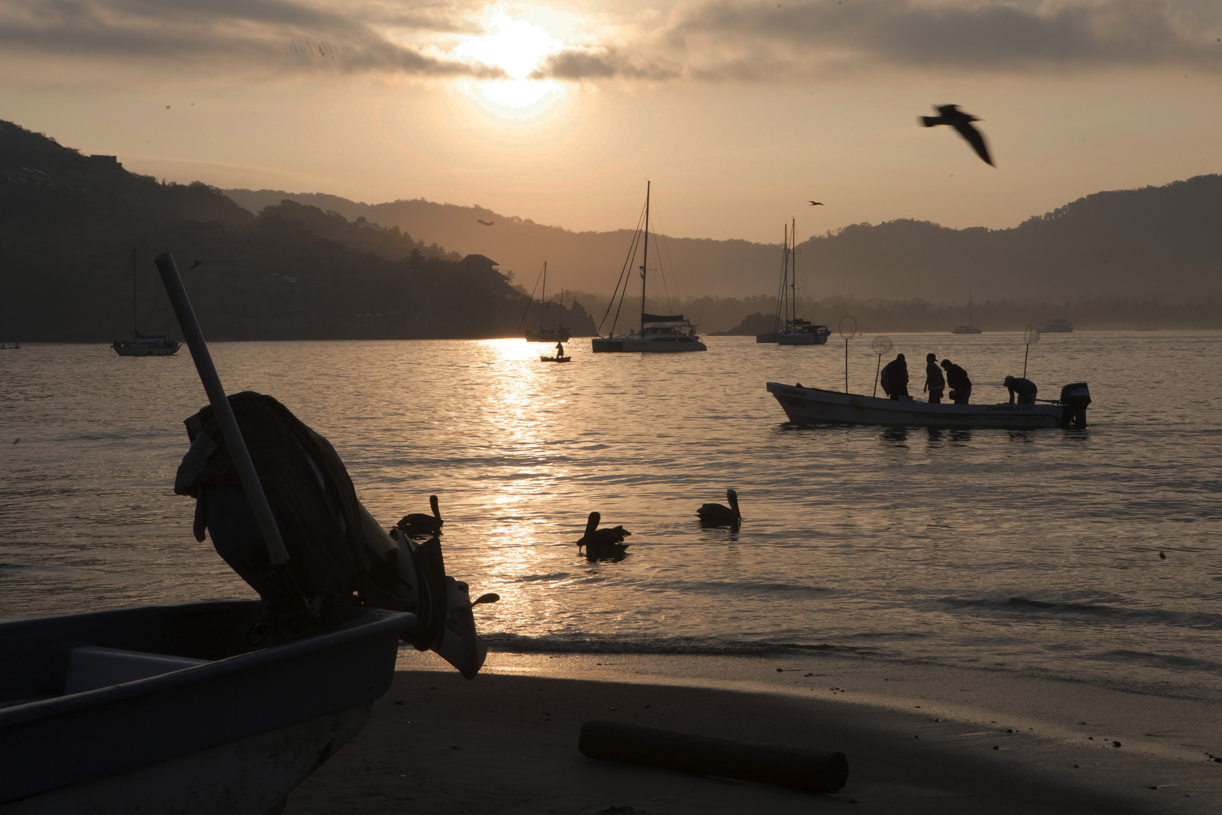  As the sun begins to rise over the calm bay, fishing boats return from a night's work to Playa Principal, the main beach in the center of town of Zihuatanejo. ©Gail Fisher&nbsp; 