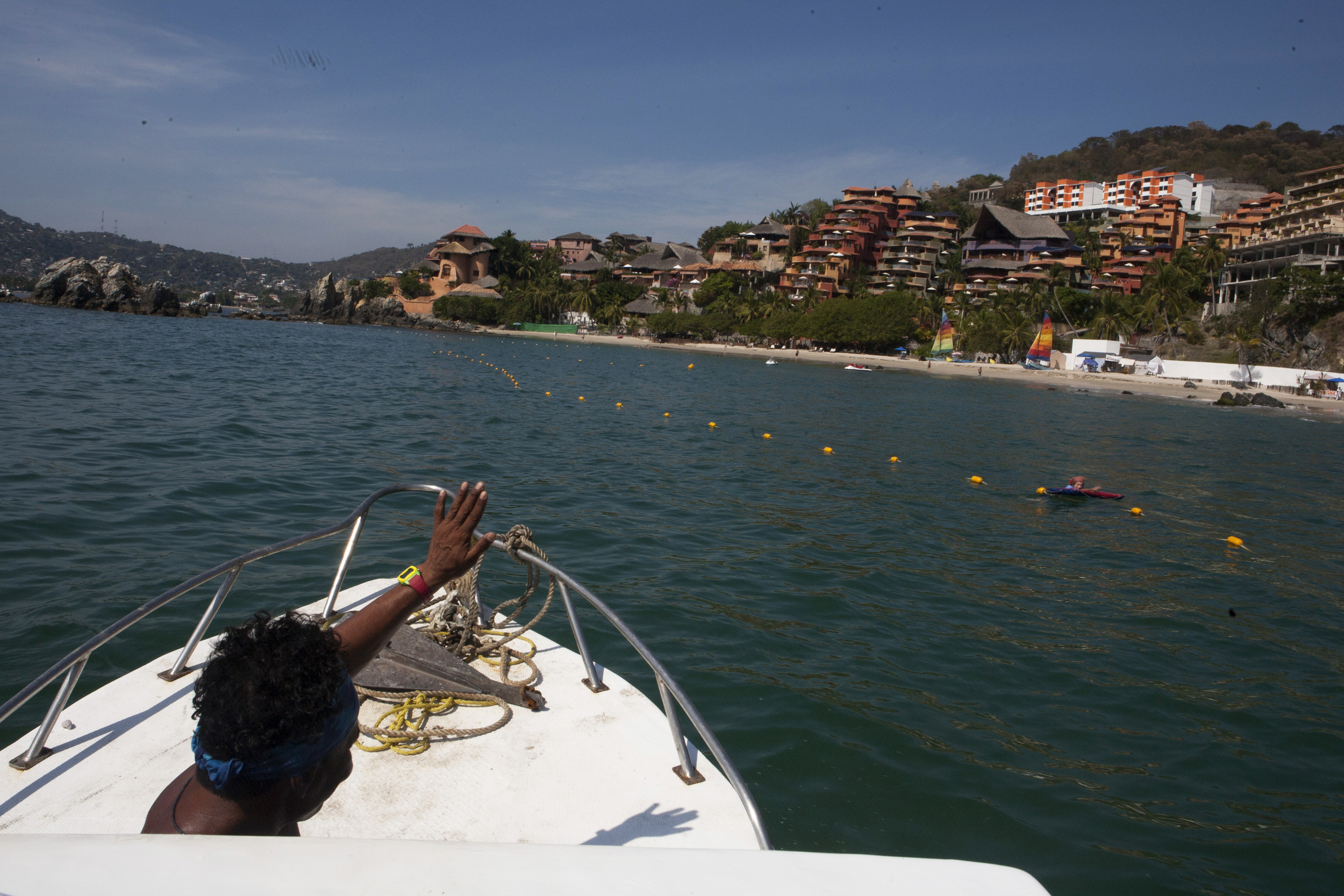  From the perceptive of the "Reny," our fishing boat, Polo Flores, guide, waves to a swimmer as he approaches Club Intrawest Vacation Club on the shore of Playa La Ropa where we were staying for the week in Zihua. ©Gail Fisher&nbsp; 