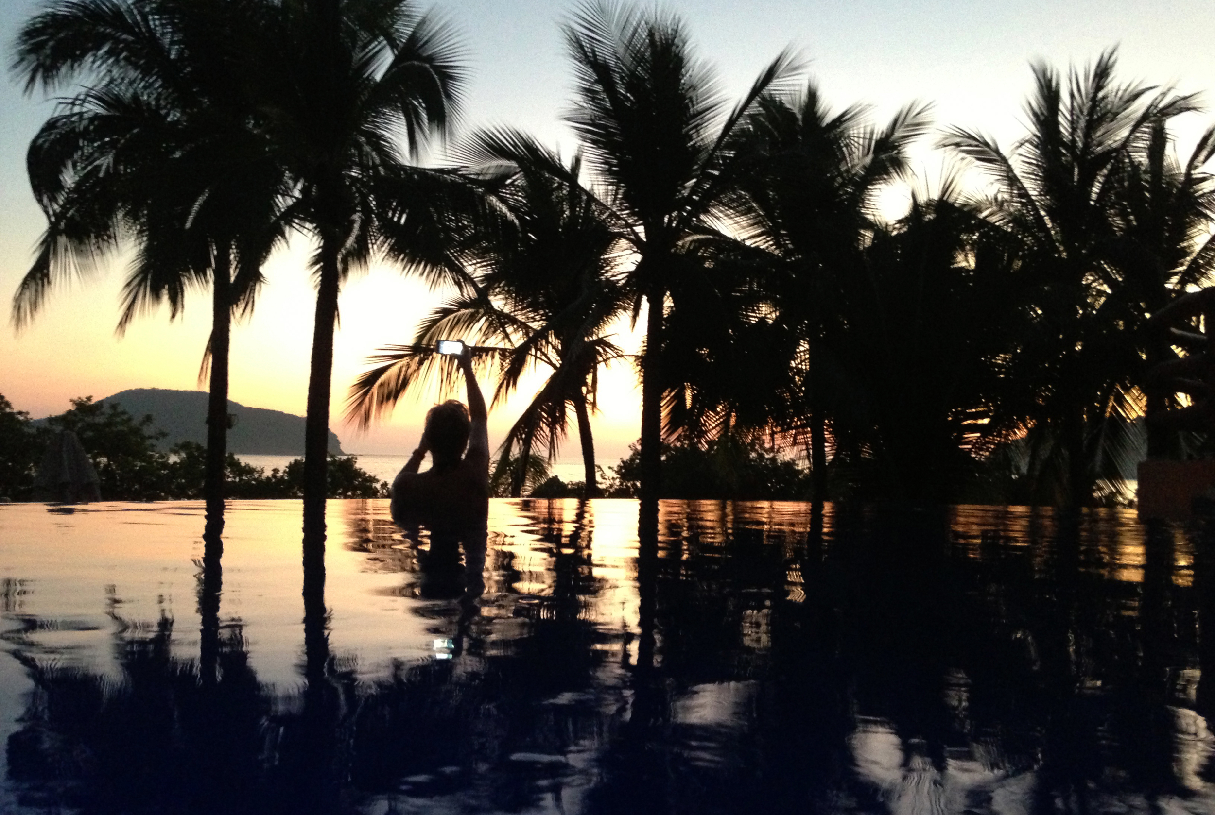  Reflecting palm fronds on a pool of tranquil blue and pink, the perspective plays tricks with one's mind.&nbsp; Where the infinity pool at Club Intrawest ends, the sea begins, as dusk descends over Playa La Ropa in Zihuatanejo, Mexico. ©Gail Fisher 