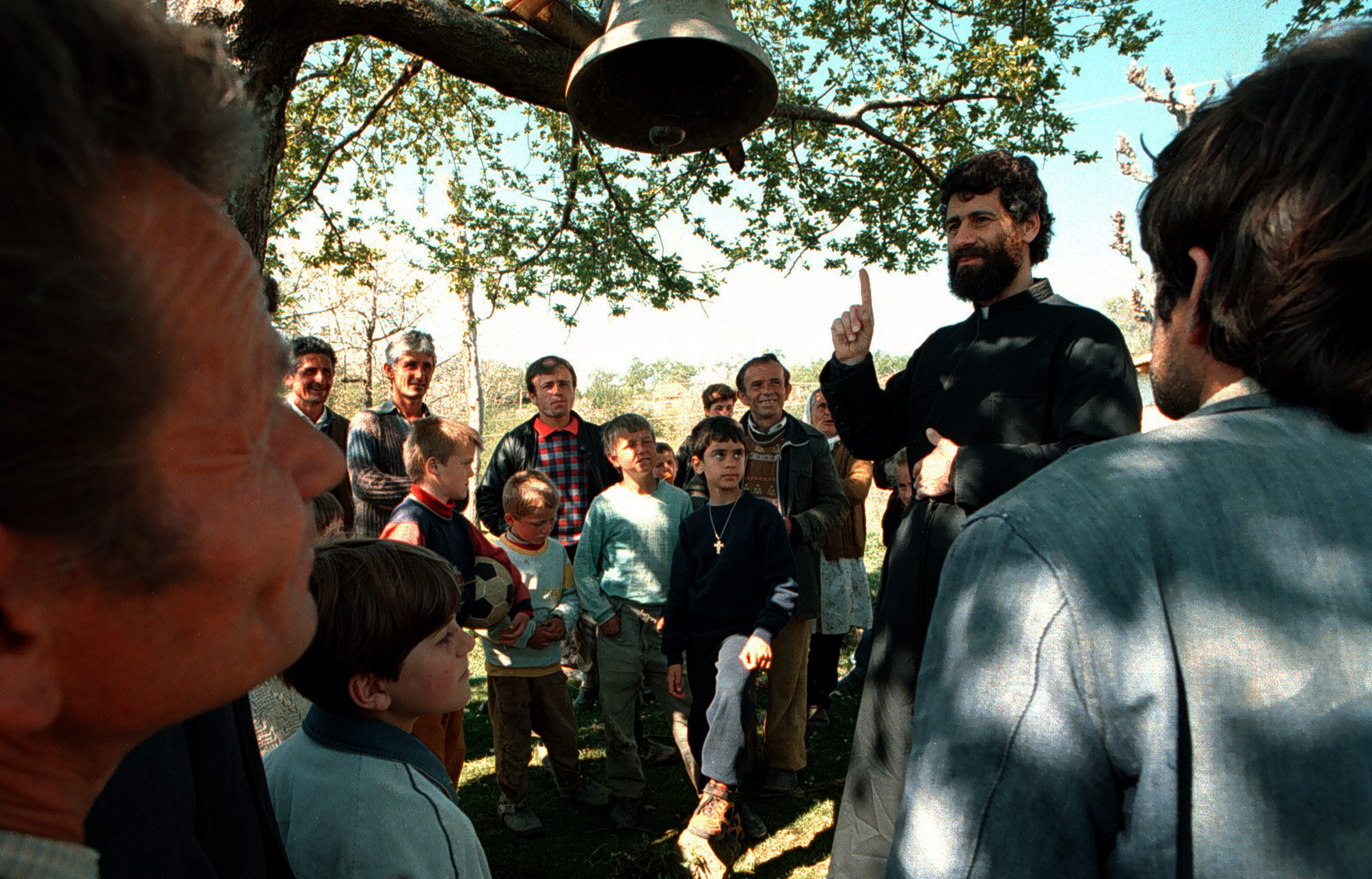  Villagers of Jeronisht gather around Father Martin Ritsi, an orthodox priest from Orange County who move to the Balkan Nation three years ago to help make a difference in their lives. ©Gail Fisher Los Angeles Times 