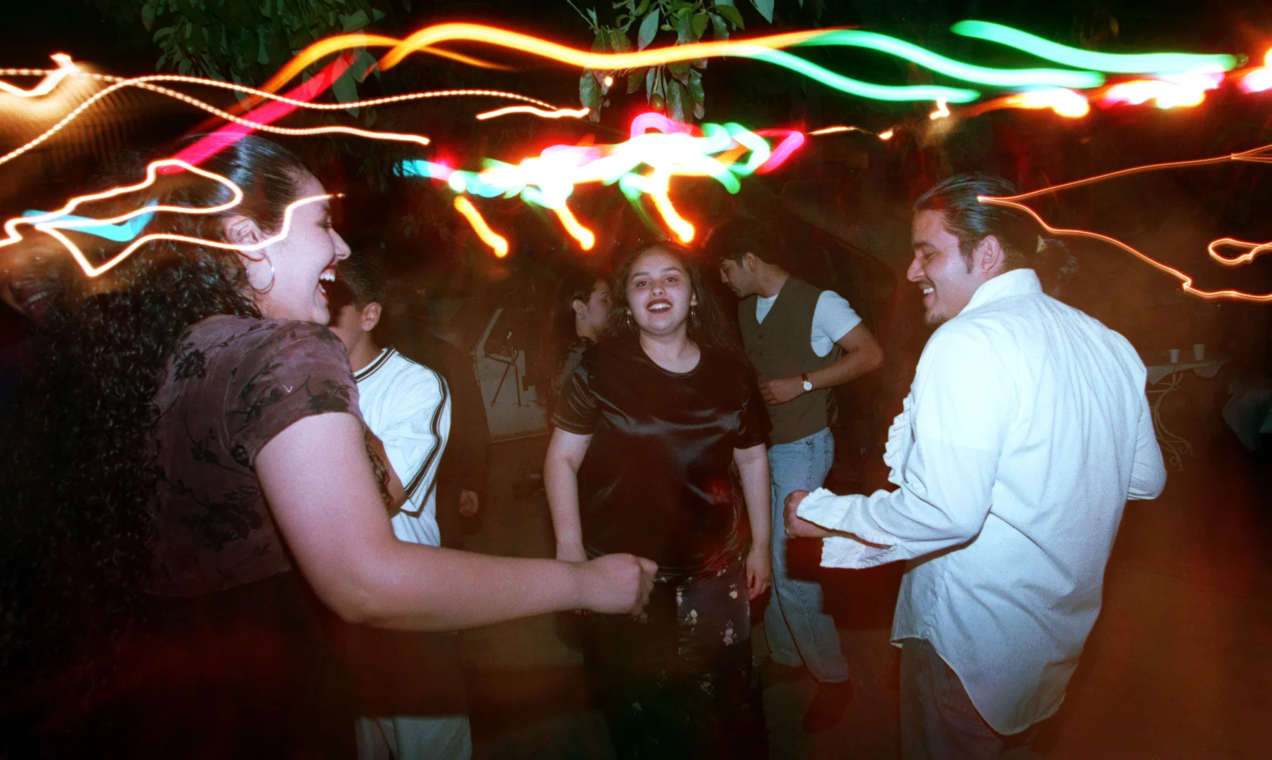 Araceli, left, with friends and family dance the night away in Santa Ana at a cousin's first communion party. ©Gail Fisher Los Angeles Times