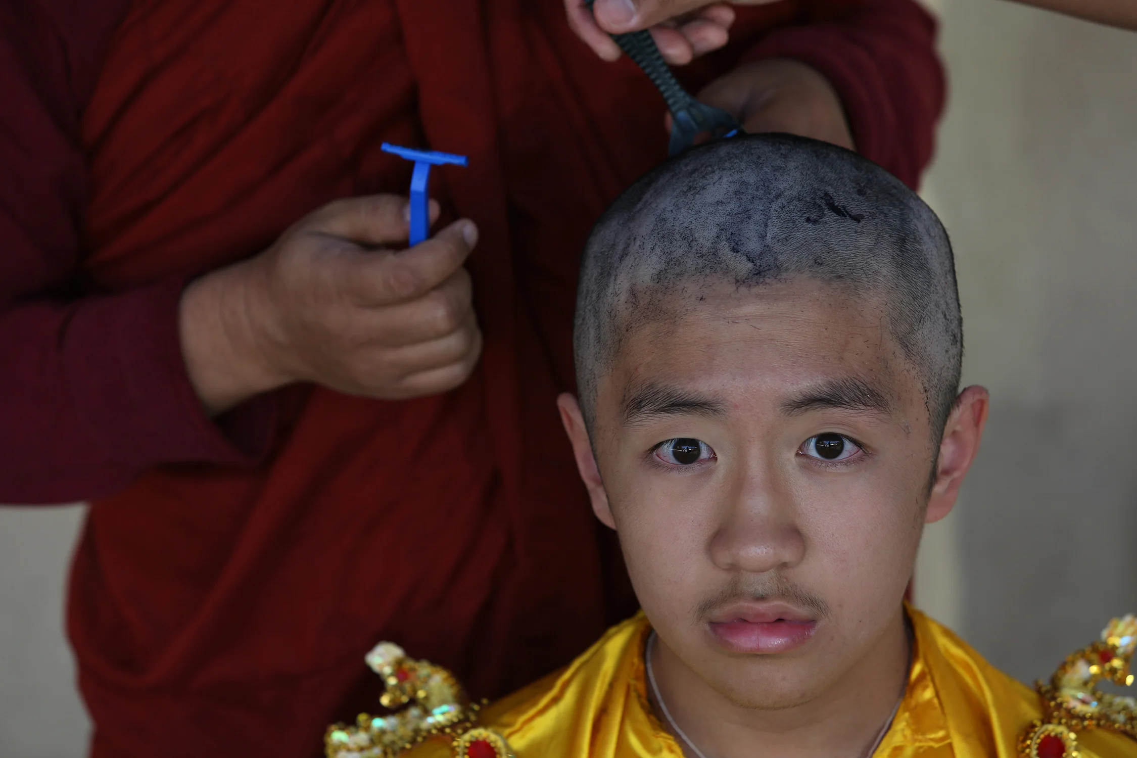 Ashin Gunissara shaves the head of Filbert Win Min Aung. The shaving of the head symbolizes giving up vanity. © Gail Fisher for Los Angeles Times