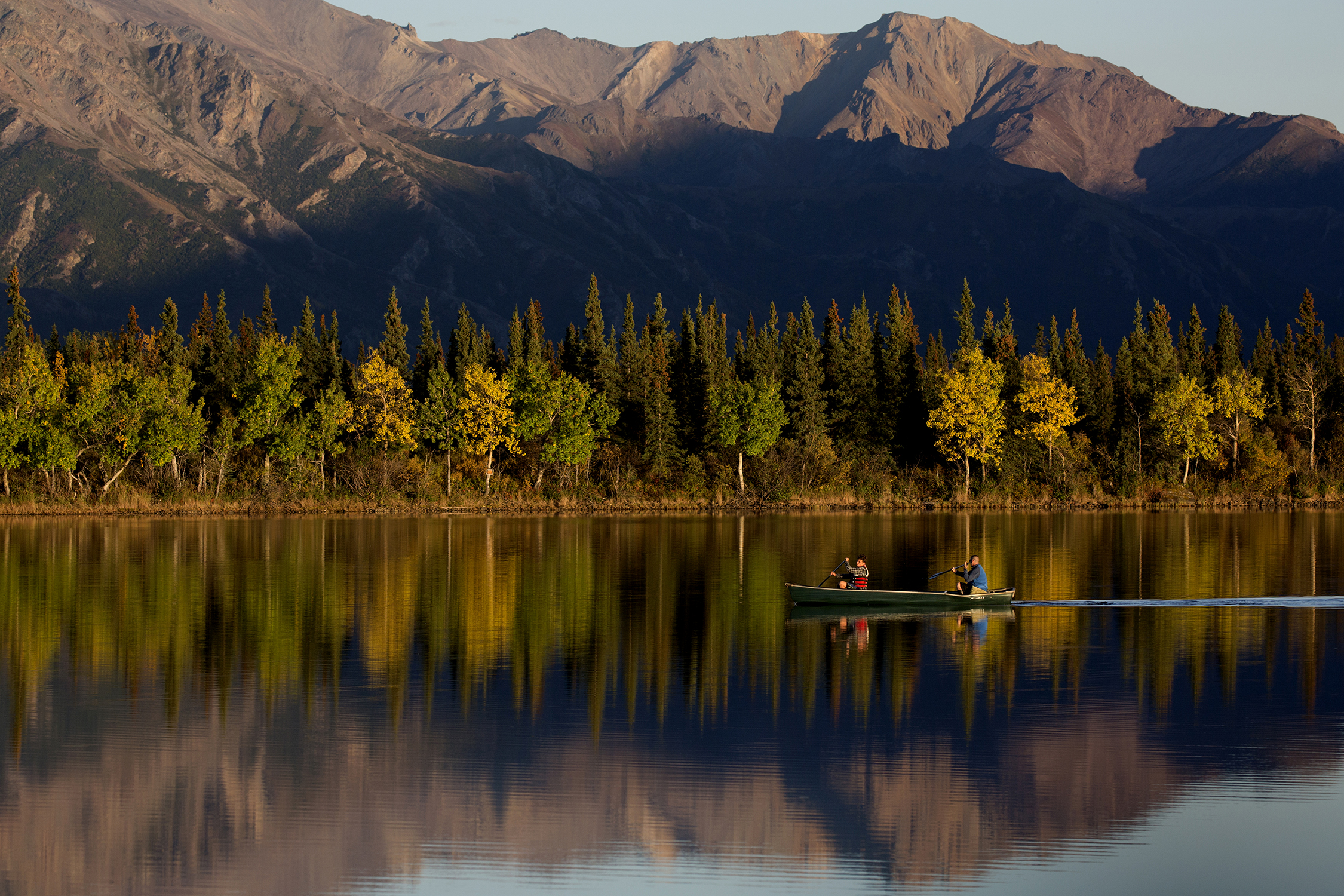  Kayakers glide over calm mirror-like Otto Lake with autumn turning leaves into a yellow hue, located a couple miles outside Healy, Alaska.&nbsp; © Photo by Gail Fisher    