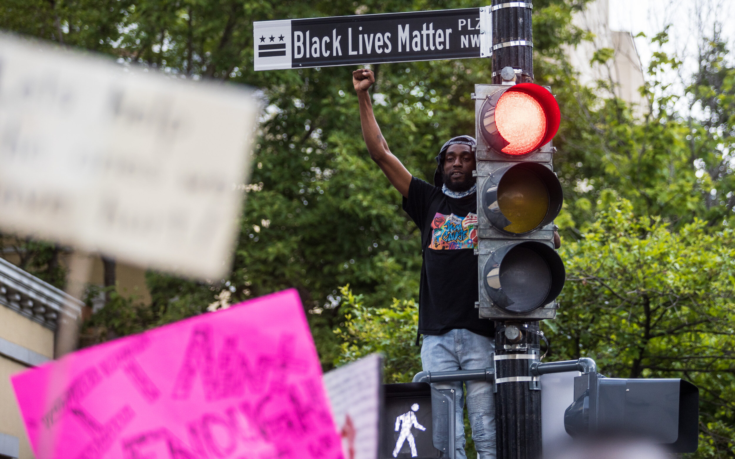  A protester climbs up to a street sign at the newly renamed Black Lives Matter Plaza near the White House in Washington, D.C., June 6, 2020. 