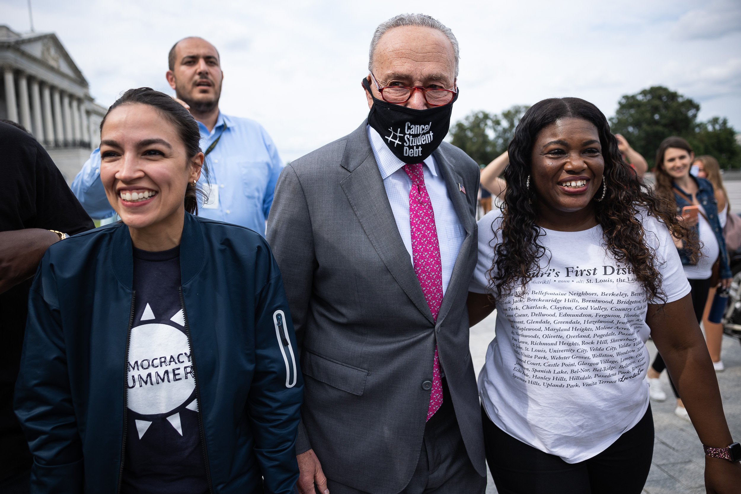  Reps. Alexandria Ocasio-Cortez (D-N.Y.) and Cori Bush (D-Mo.) celebrate with Senate Majority Leader Chuck Schumer (D-N.Y.) after the Biden administration announced an extension of the federal eviction moratorium Aug. 3, 2021. 