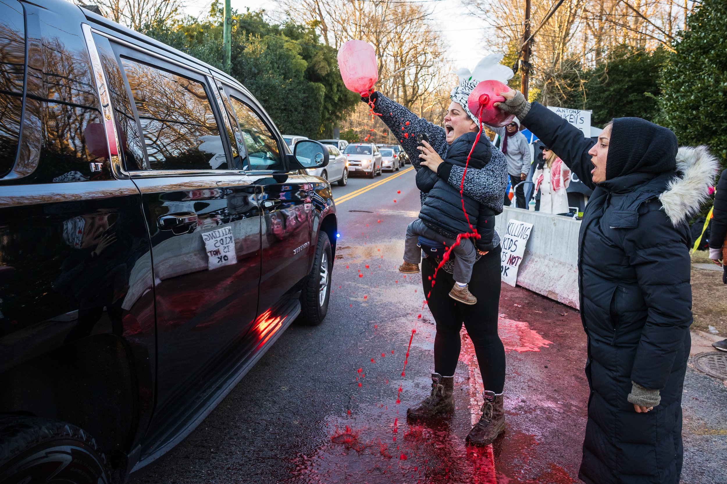  Hazami Barmada, holding her one-year-old son, Kayden, and Fatima Showkatian pour fake blood in front of a vehicle carrying Secretary of State Antony Blinken as it arrives at Blinken's home in McLean, Va., Feb. 14, 2024. Barmada and Showkatian were p