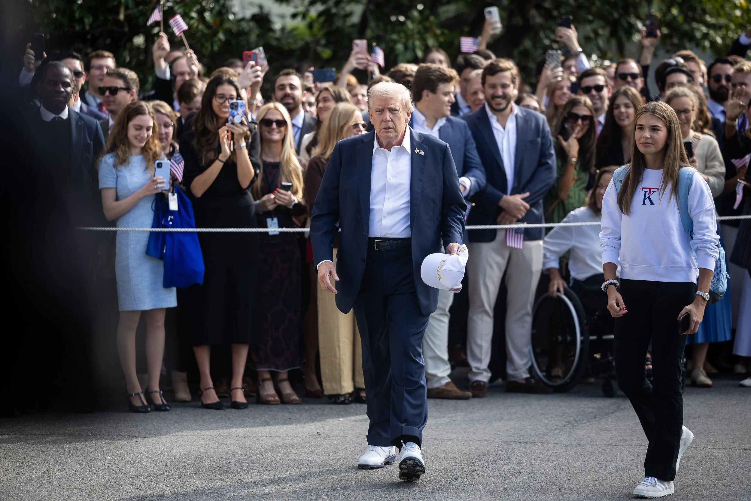  President Donald Trump turns to speak with reporters after greeting supporters on the South Lawn of the White House Sept. 26, 2025. At right, the president's granddaughter, Kai Trump, is seen. 