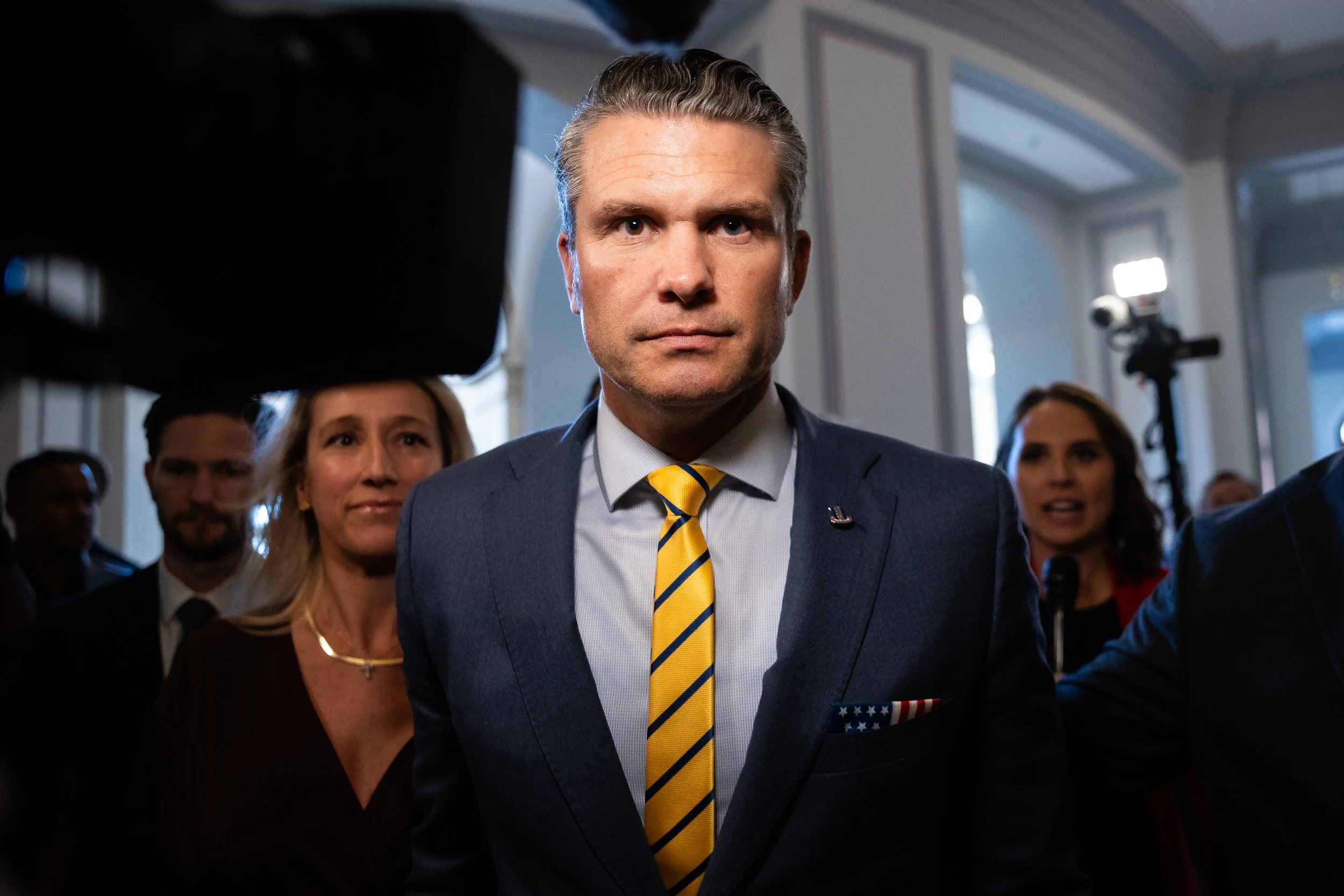  Pete Hegseth, President-elect Donald Trump's nominee for secretary of defense, is surrounded by his entourage and pursued by journalists as he walks to a meeting on Capitol Hill Dec. 3, 2024. At left, Hegseth's wife, Jennifer Rauchet, is seen. 