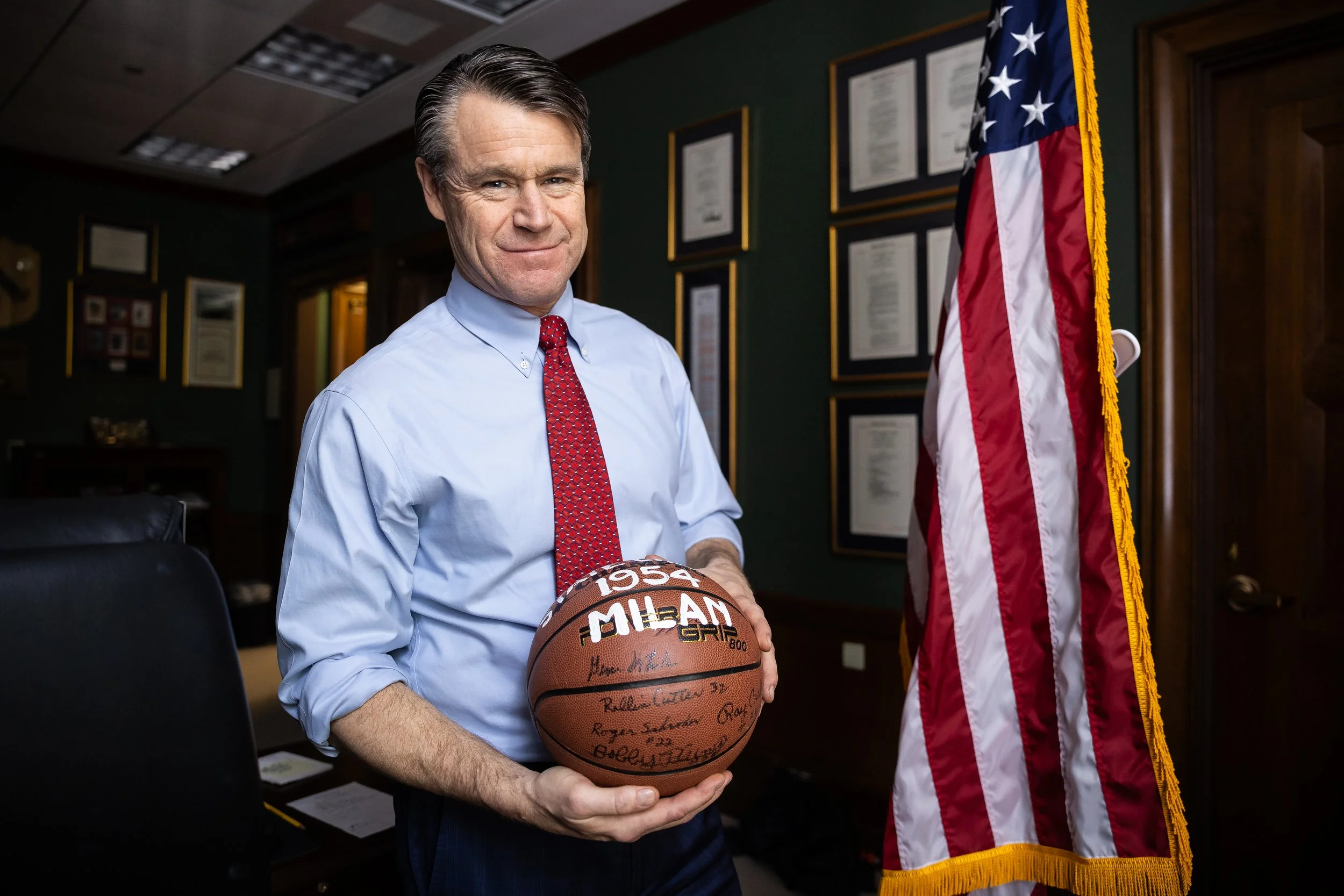  Sen. Todd Young (R-Ind.) stands in his Capitol Hill office on March 21, 2024 as he holds a basketball signed by members of the 1954 Milan High School team, which won the Indiana state championship by beating the team from the much larger Muncie Cent