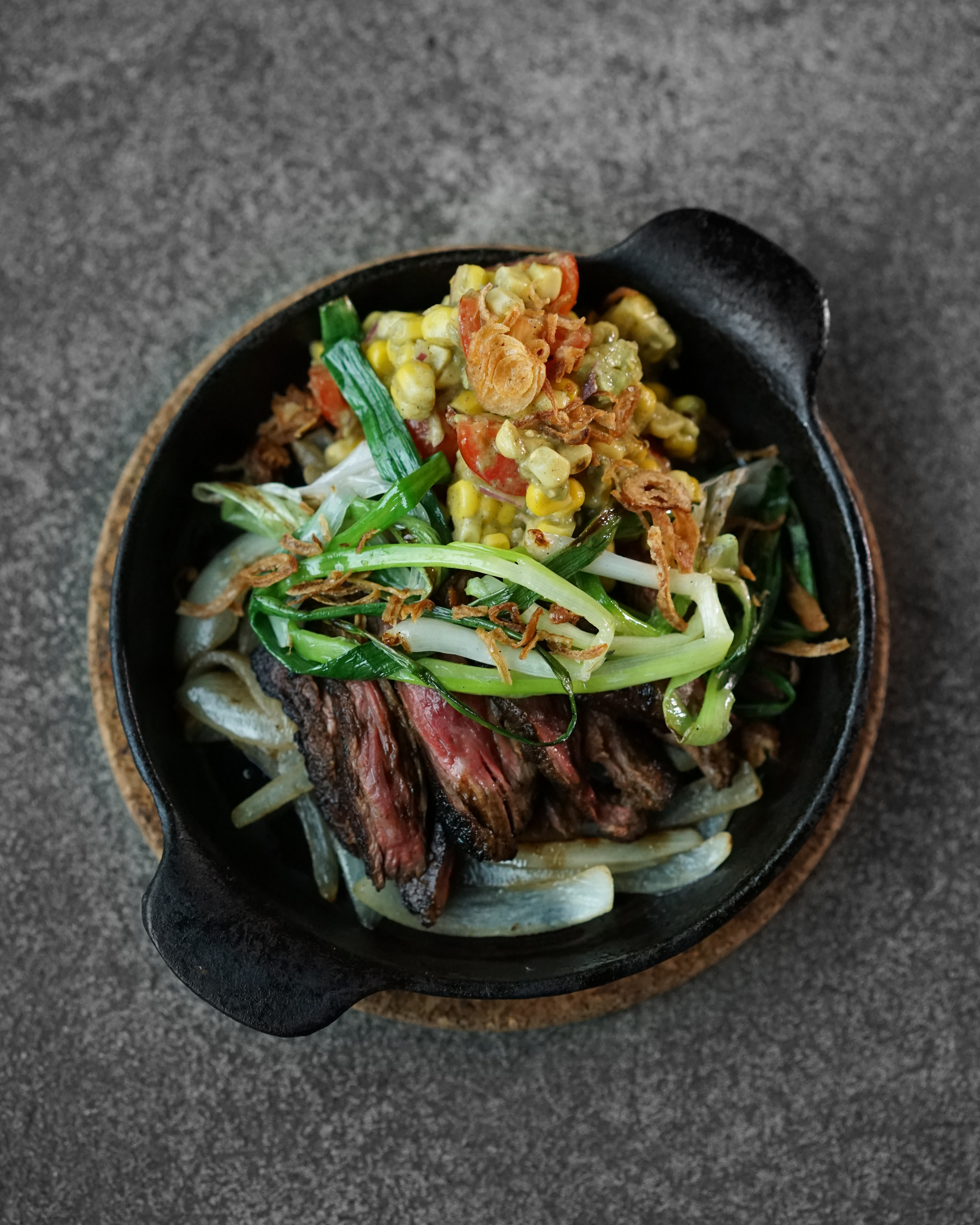 Marinated Skirt Steak / Grilled Corn Salsa Marinated skirt steak seared and served over a savory bed of onions. Served with our grilled corn salsa and roasted green onions, it's the perfect main to share with your friends.