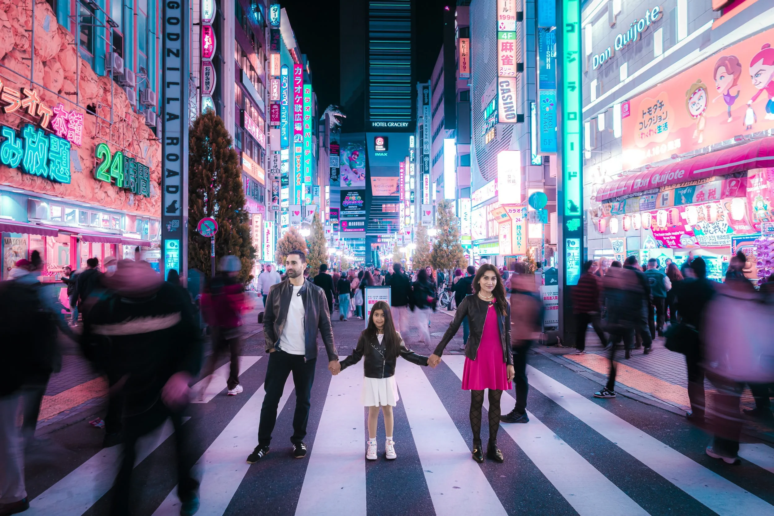 Family of three holding hands on a crosswalk in Kabukicho, Tokyo, with the Godzilla Road neon skyline in a cyberpunk-style photoshoot