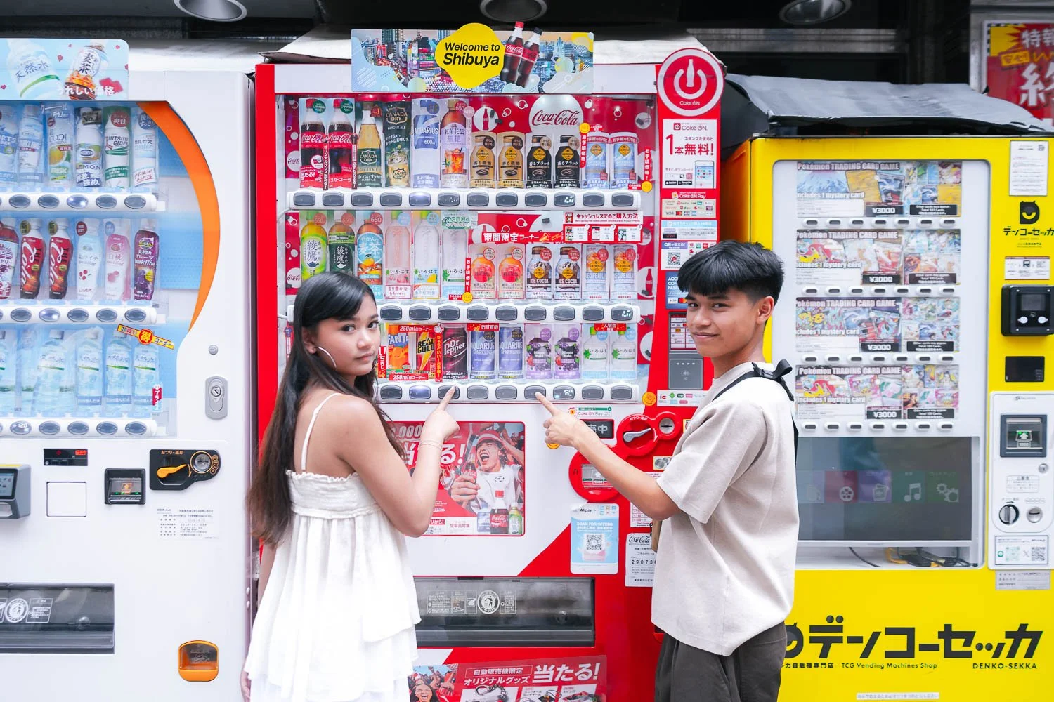 Teen siblings pointing at a Japanese vending machine during a candid Shibuya photoshoot
