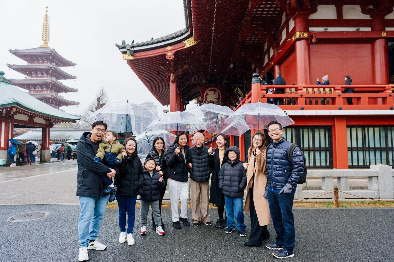 Family holding umbrellas in front of Sensō-ji Temple during a rainy day Tokyo photoshoot