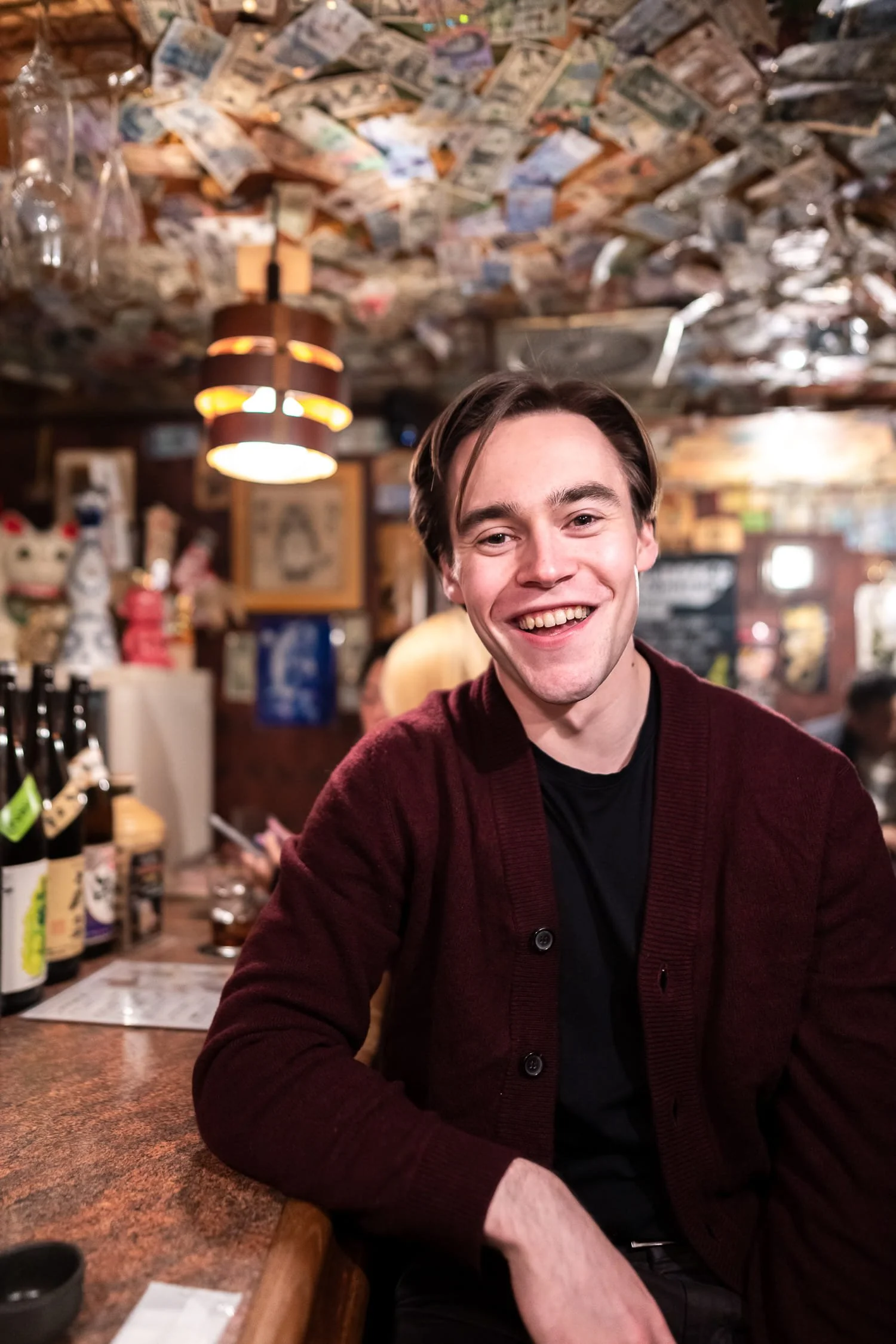 European traveler smiling at a camera while sitting at the bar during a portrait photoshoot session in Shinjuku Golden Gai
