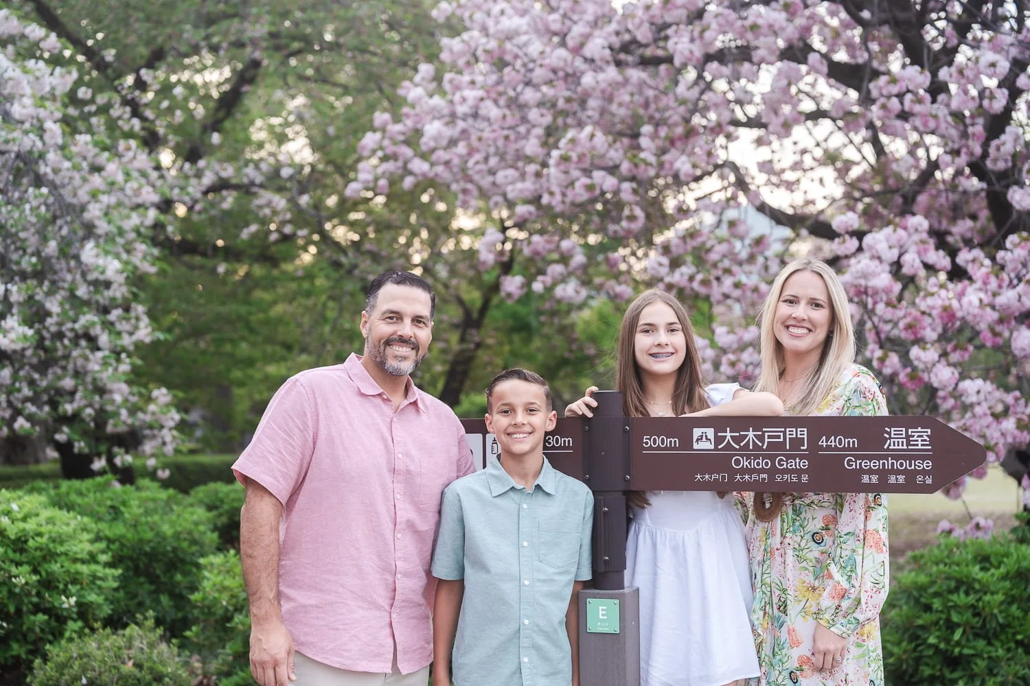 The entire family posing around Shinjuku Gyoen Park sign, this makes a great postcard for the trip to remember where they have visited