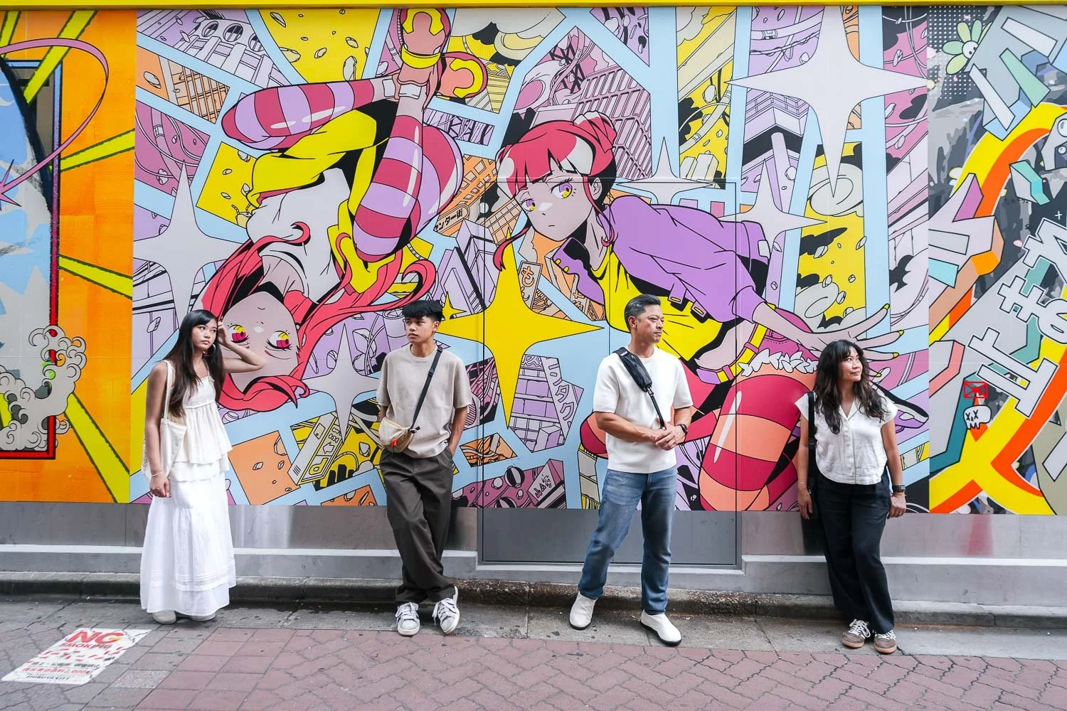 Family of four leaning against a colorful anime street mural in Shibuya, Tokyo