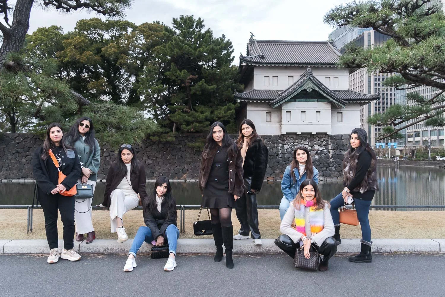 Group of women friends posing by the Imperial Palace moat and guardhouse in Tokyo
