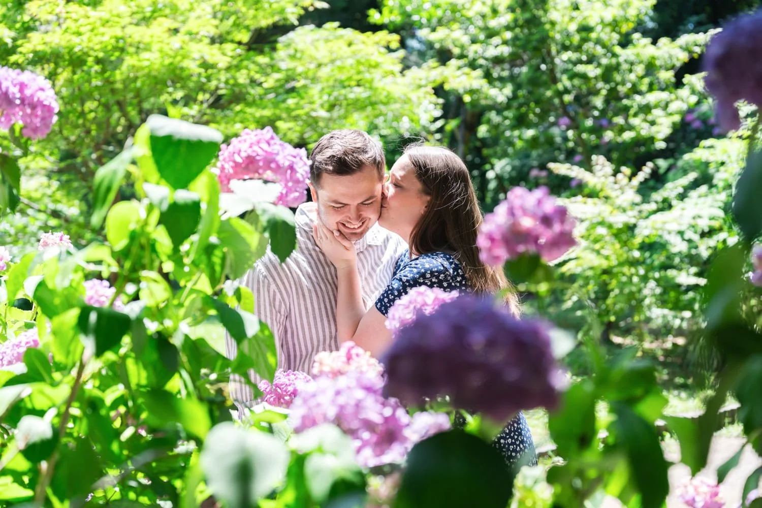Rosie kisses Jack being surrounded by colorful hydrangea