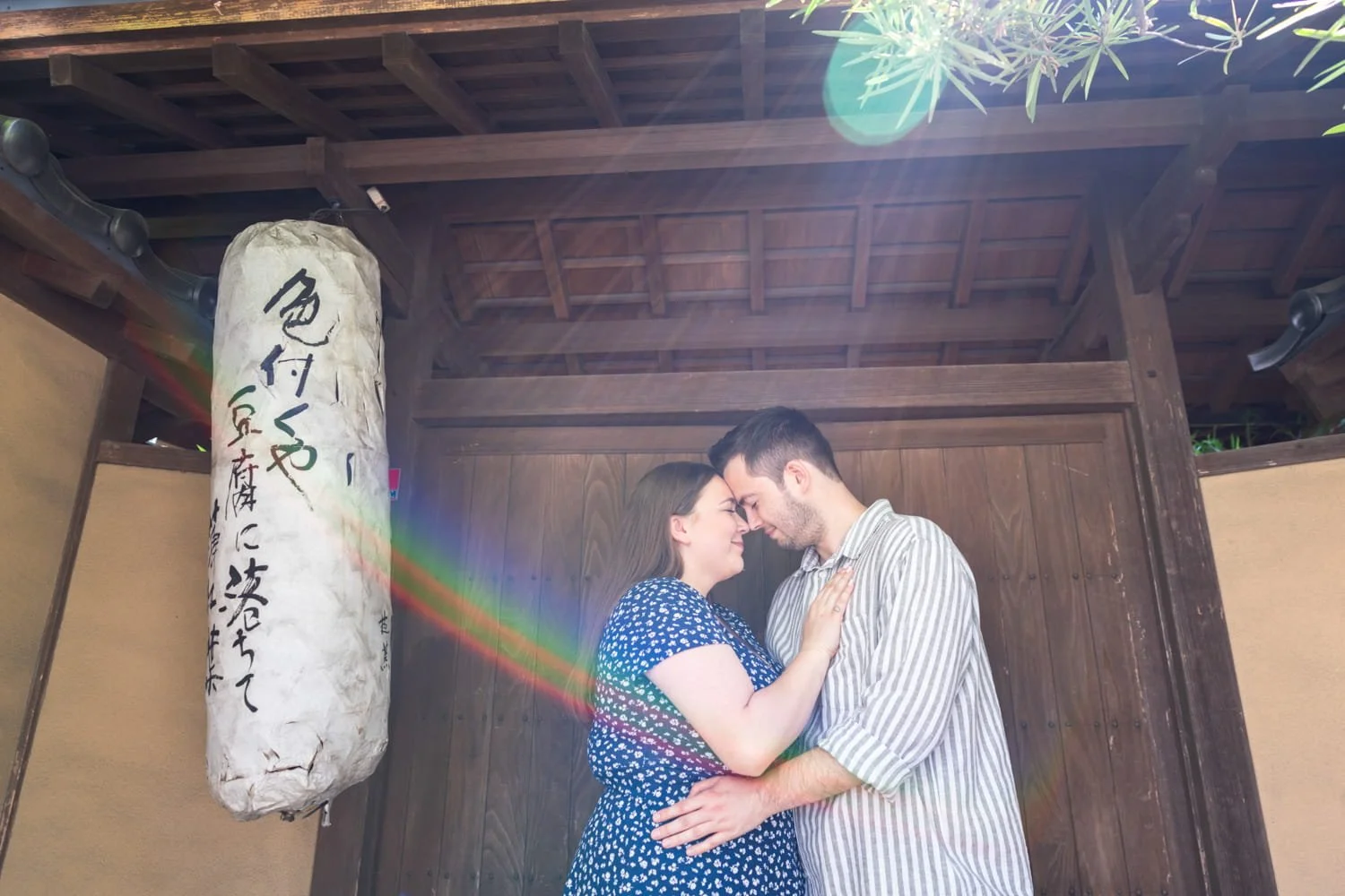 Couple hugging each other in front of traditional Japanese door under a ray of sun