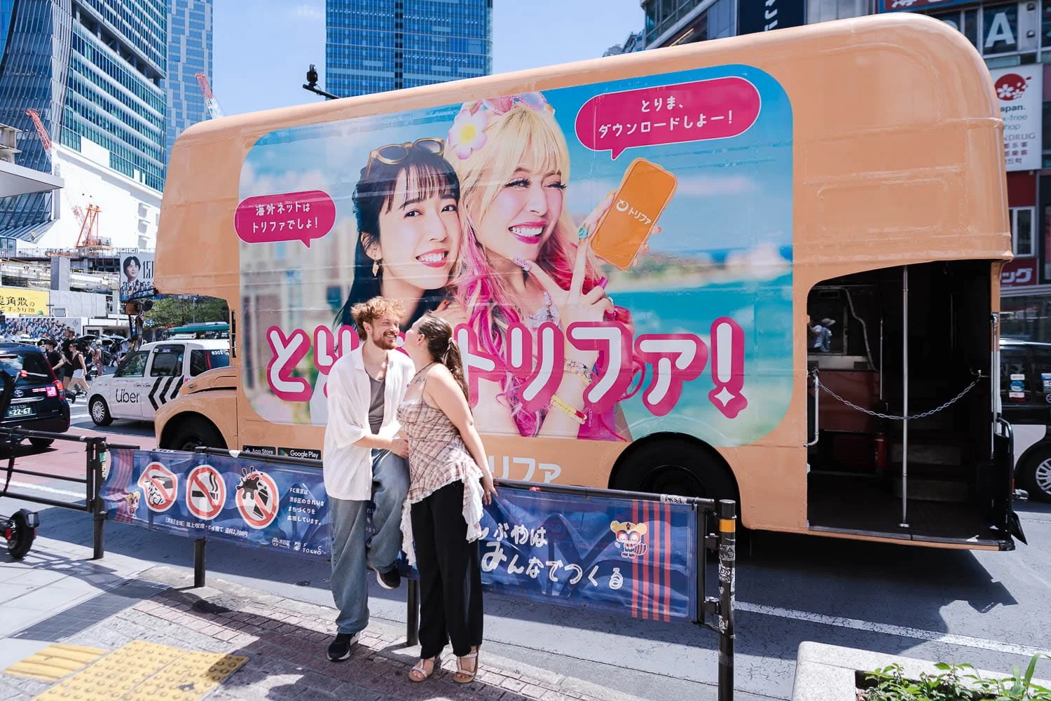 Newly engaged couple laughing together in front of colorful advertising truck in Shibuya Tokyo