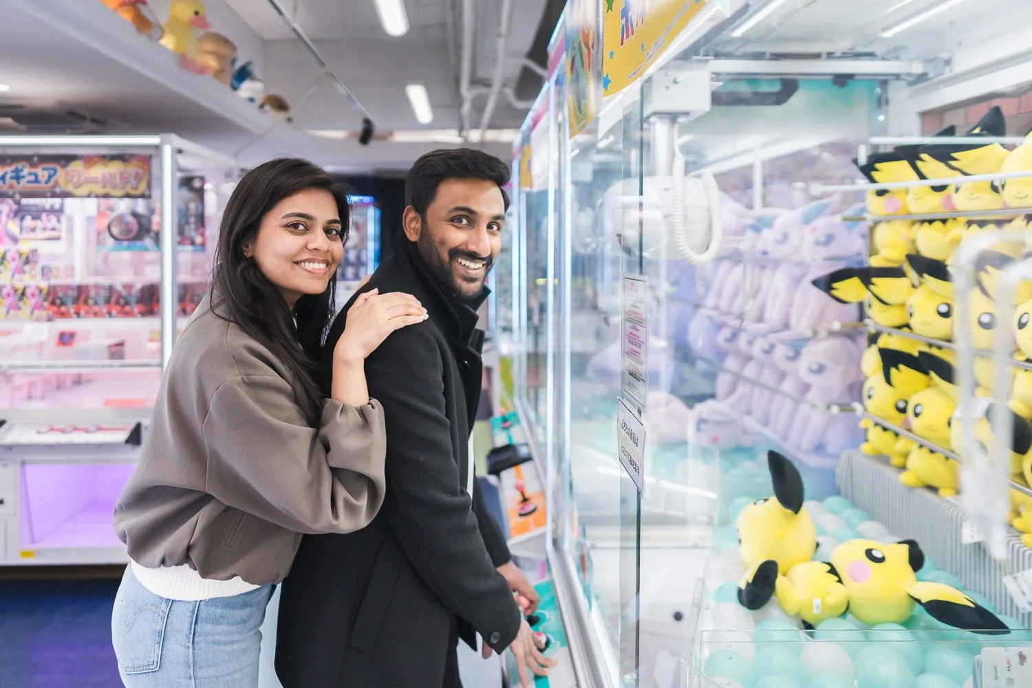 Couple having a good time trying to catch Pokemon in the game arcade
