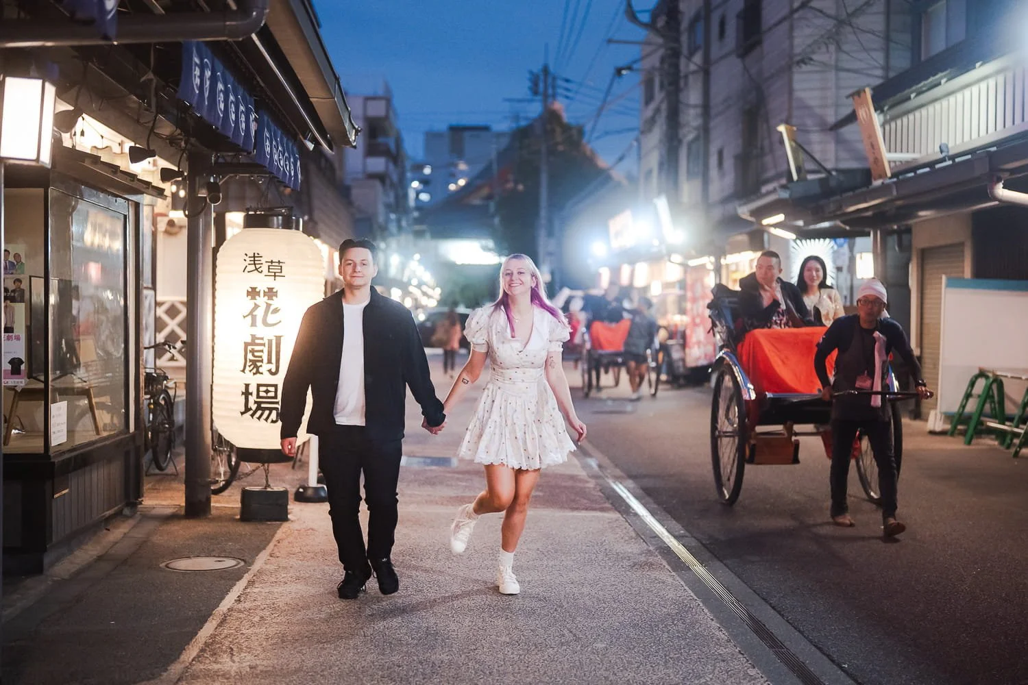 Candid shot of a couple strolling along the lantern-lit street with rickshaw passing by.