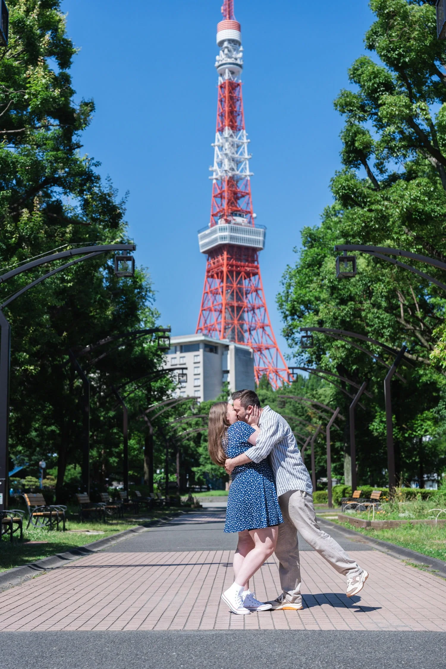 Couple kissing each other after a successful proposal at Shiba Park with Tokyo Tower in the background