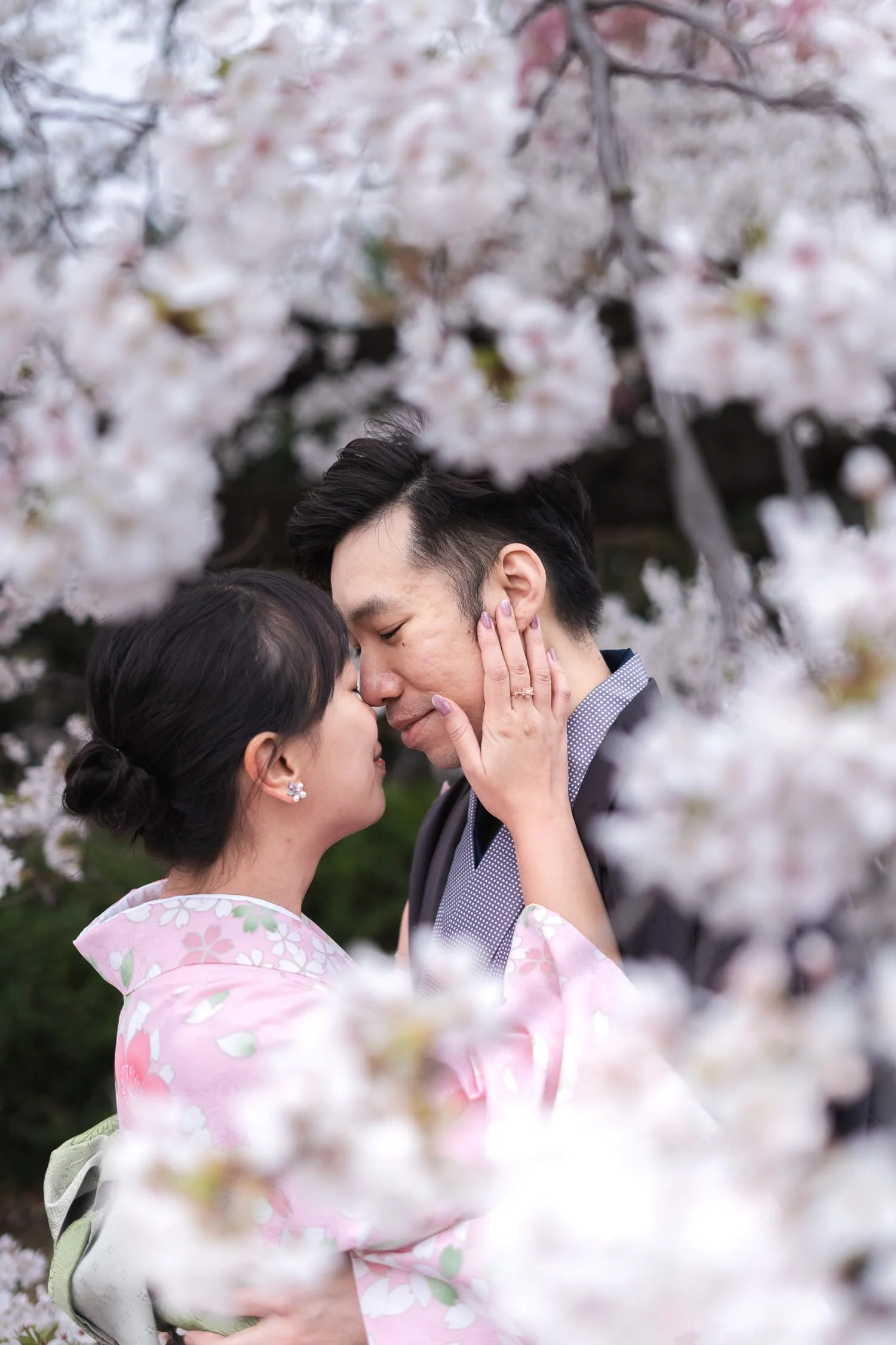 The couple was about to kiss while being surrounded by white cherry blossom flowers