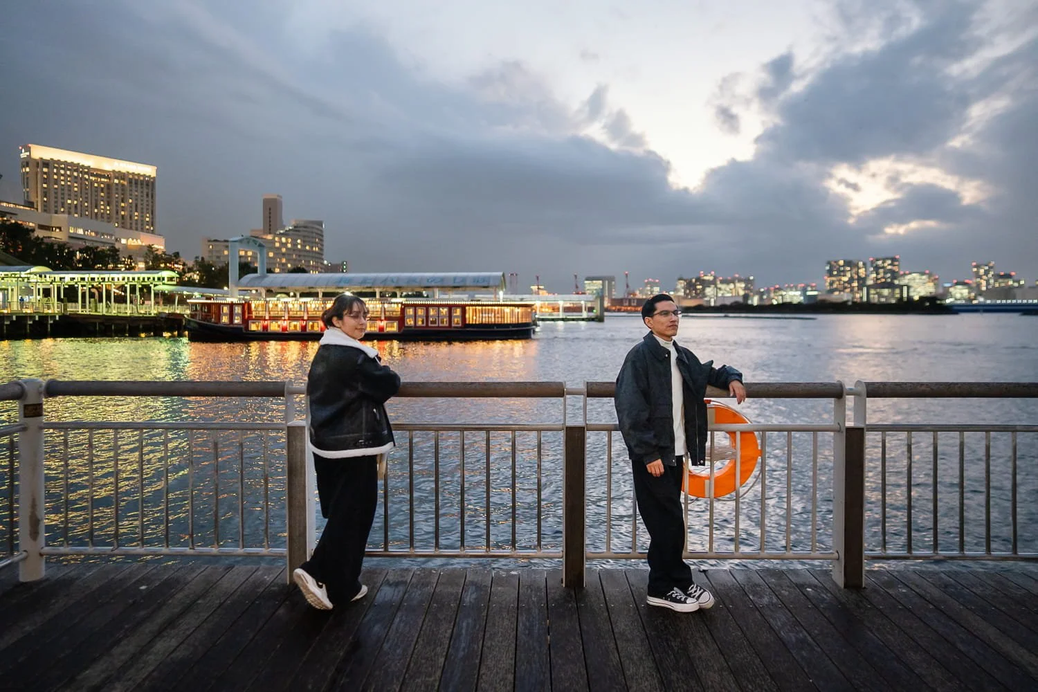 Post-engagement photoshoot on the bridge near Odaiba Beach with yakatabune boats in the background