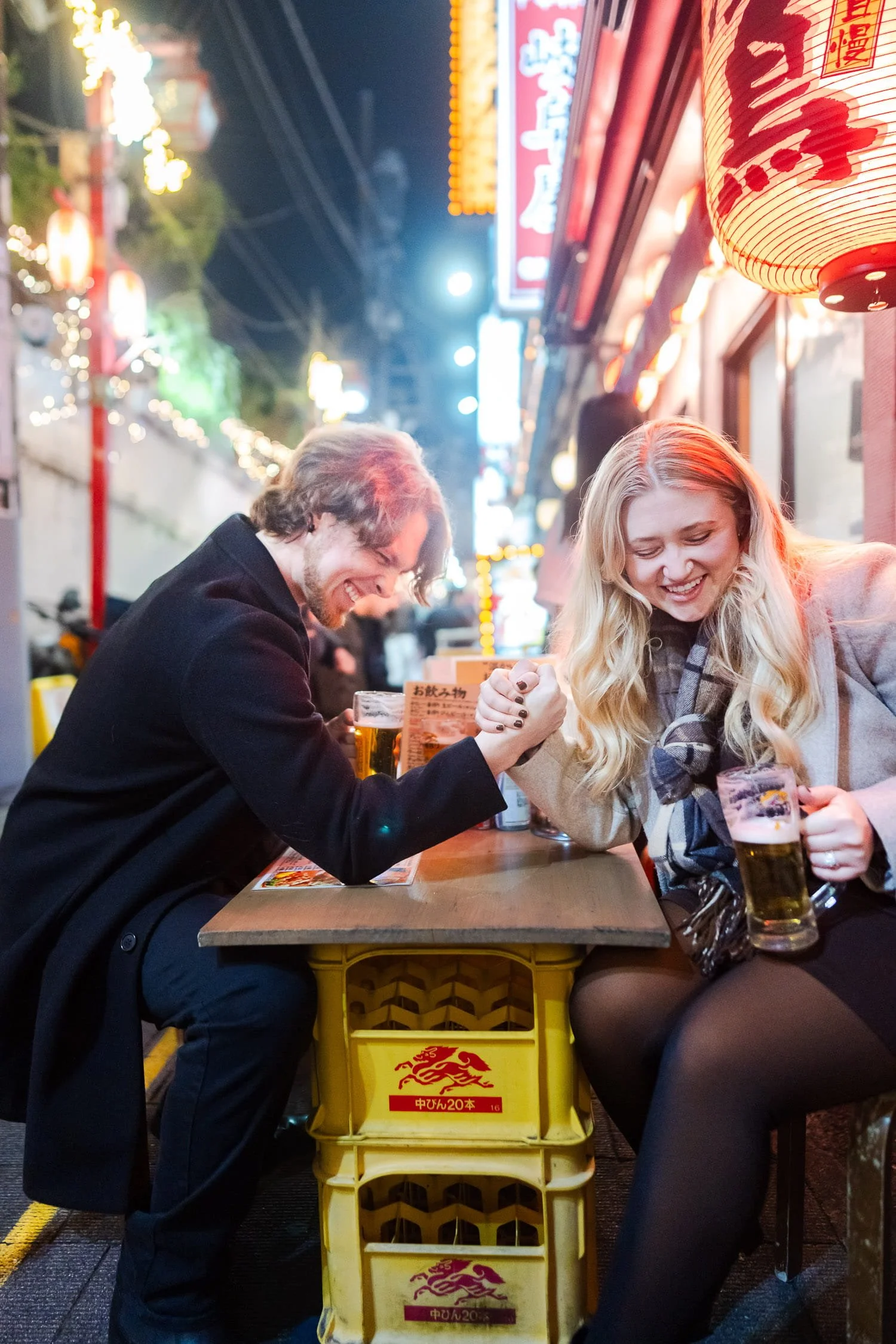 Couple having a fun date night in Shinjuku. They were having an arm wrestling while having beer at Shinjuku Omoide Yokocho