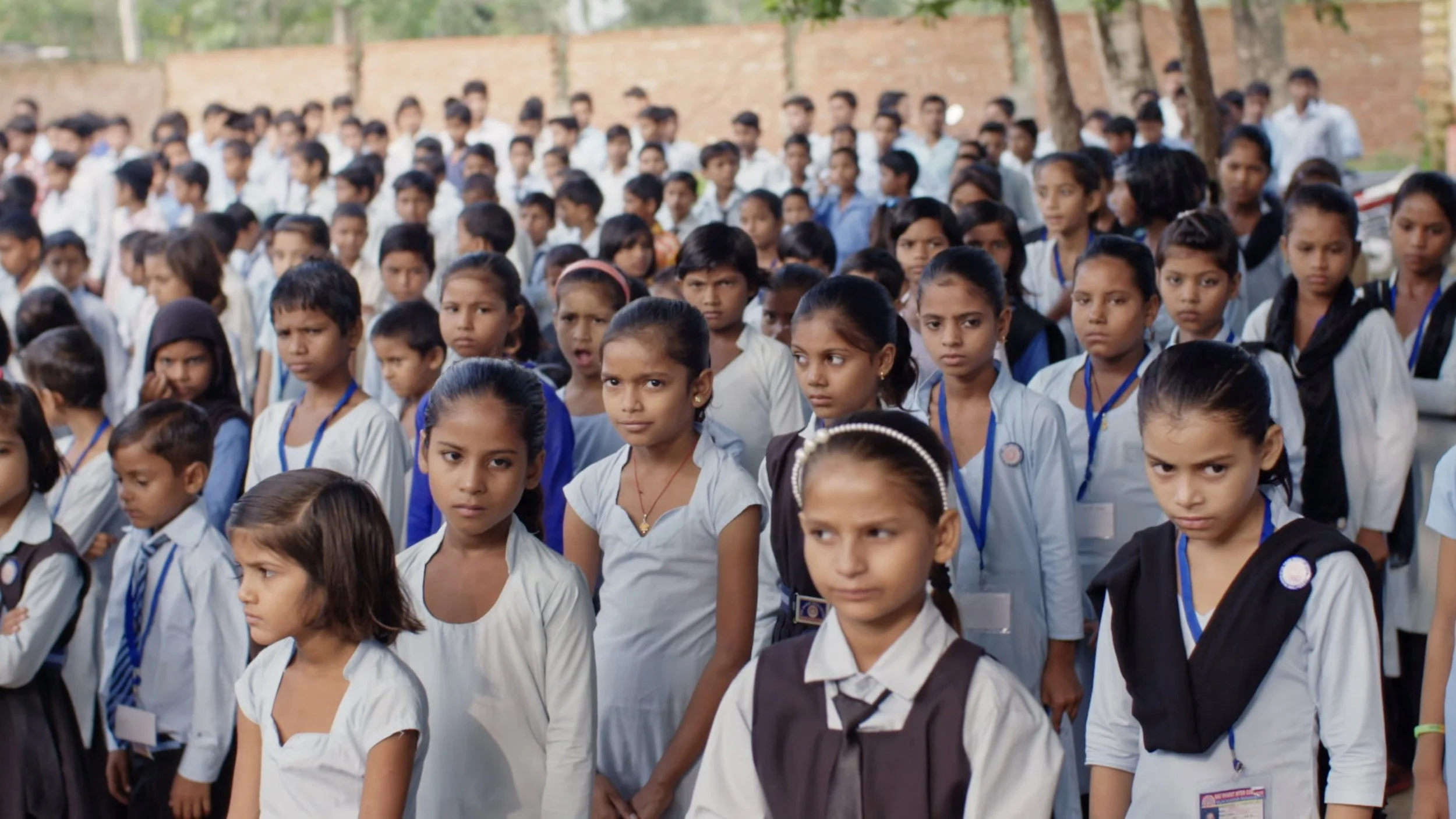 A large crowd of Indian schoolchildren are lined up outsised in rows for registration